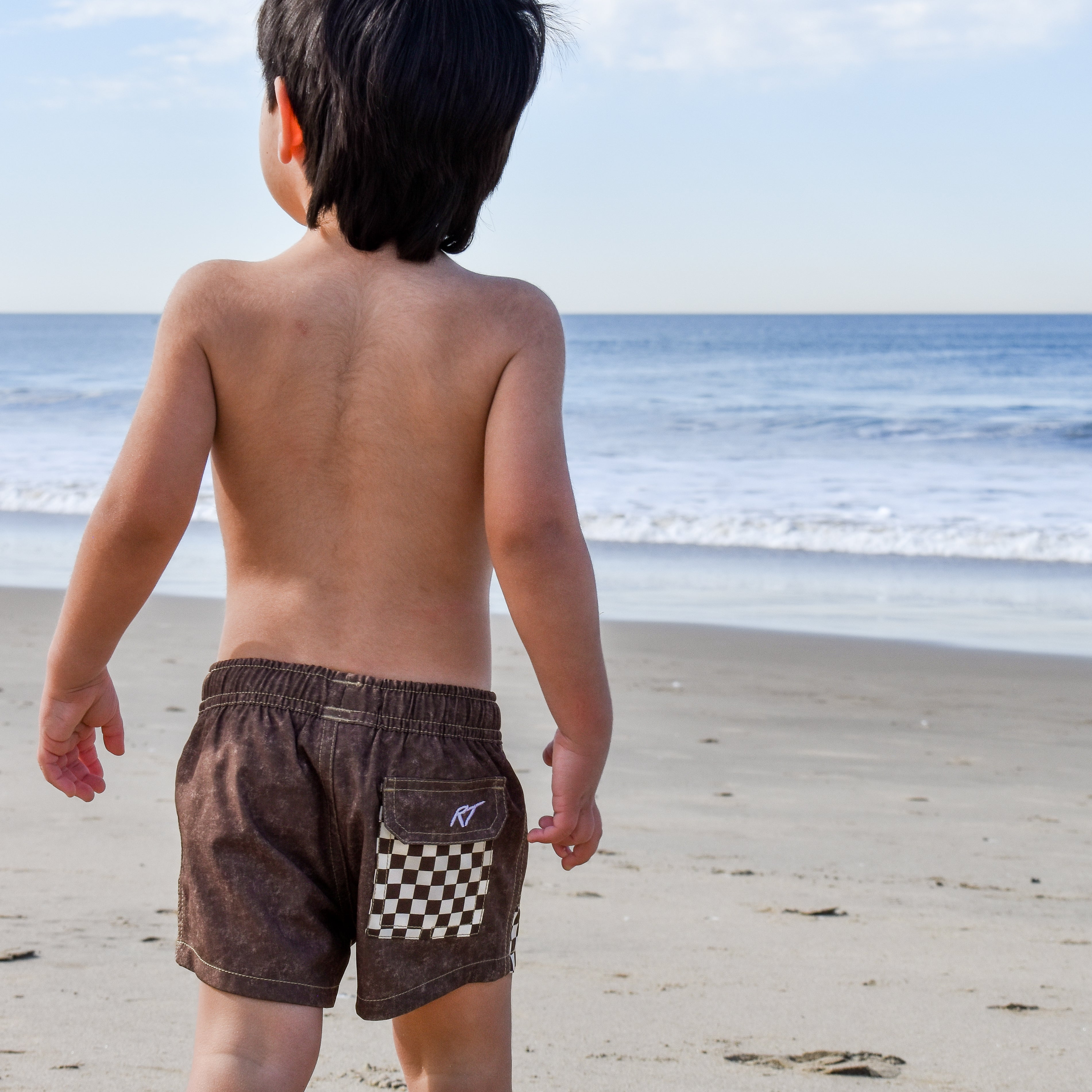 Child wearing Choco Swimmie brown checker swimsuit at the beach