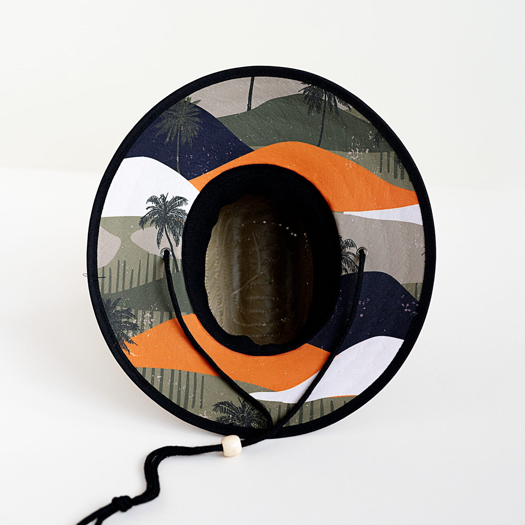bottom of RAD TODDLER straw sun hat with coastal dunes pattern featuring orange, forest green, and black colors with palm trees, designed for toddler sun protection