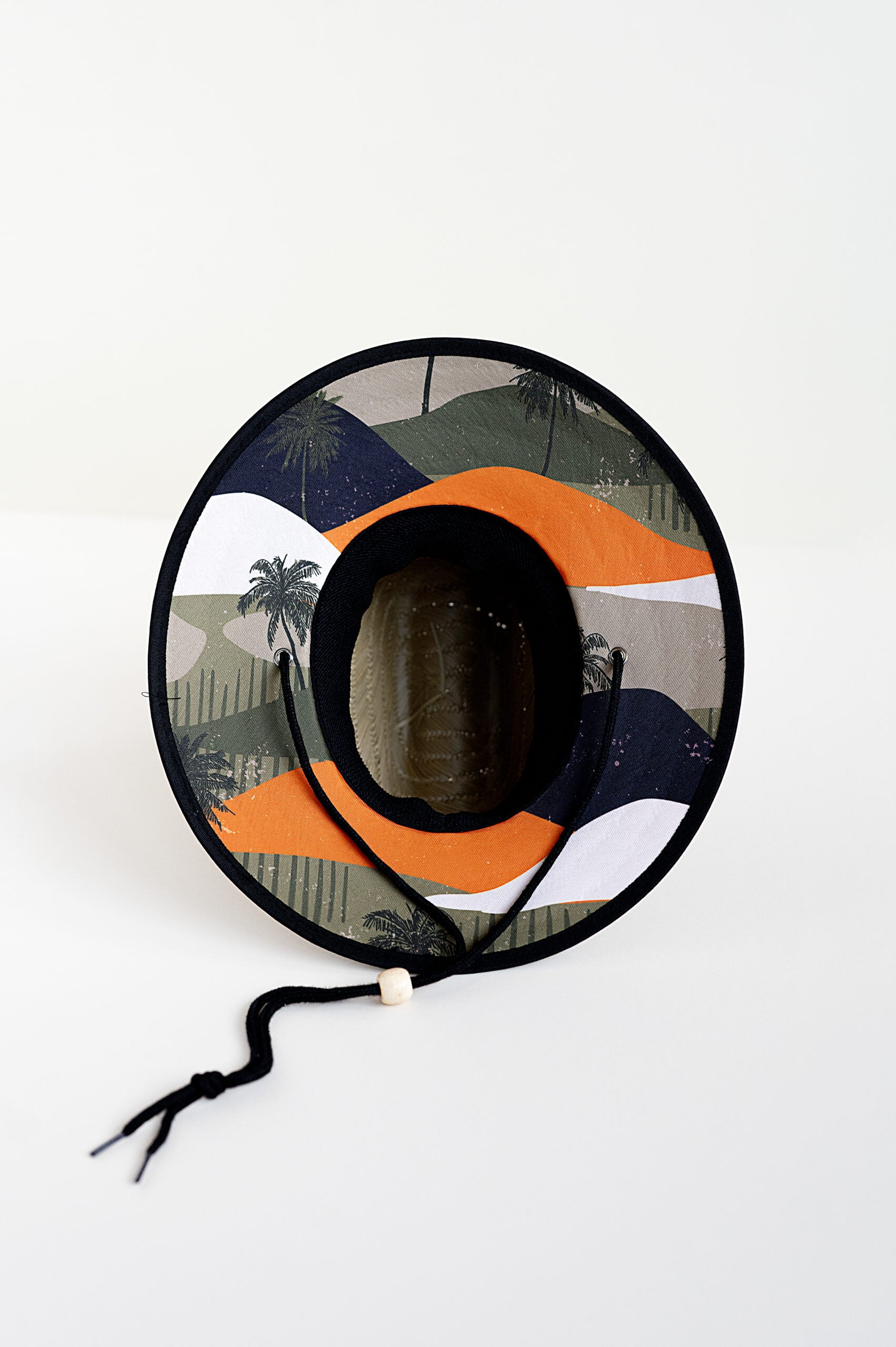 bottom of RAD TODDLER straw sun hat with coastal dunes pattern featuring orange, forest green, and black colors with palm trees, designed for toddler sun protection