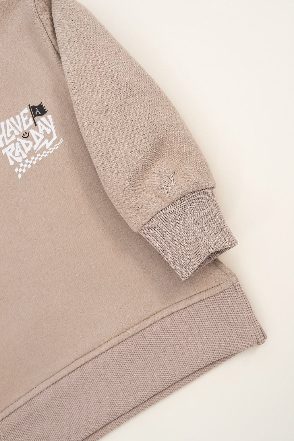 Kids beige graphic crewneck with playful white lettering and checkered design displayed on white background