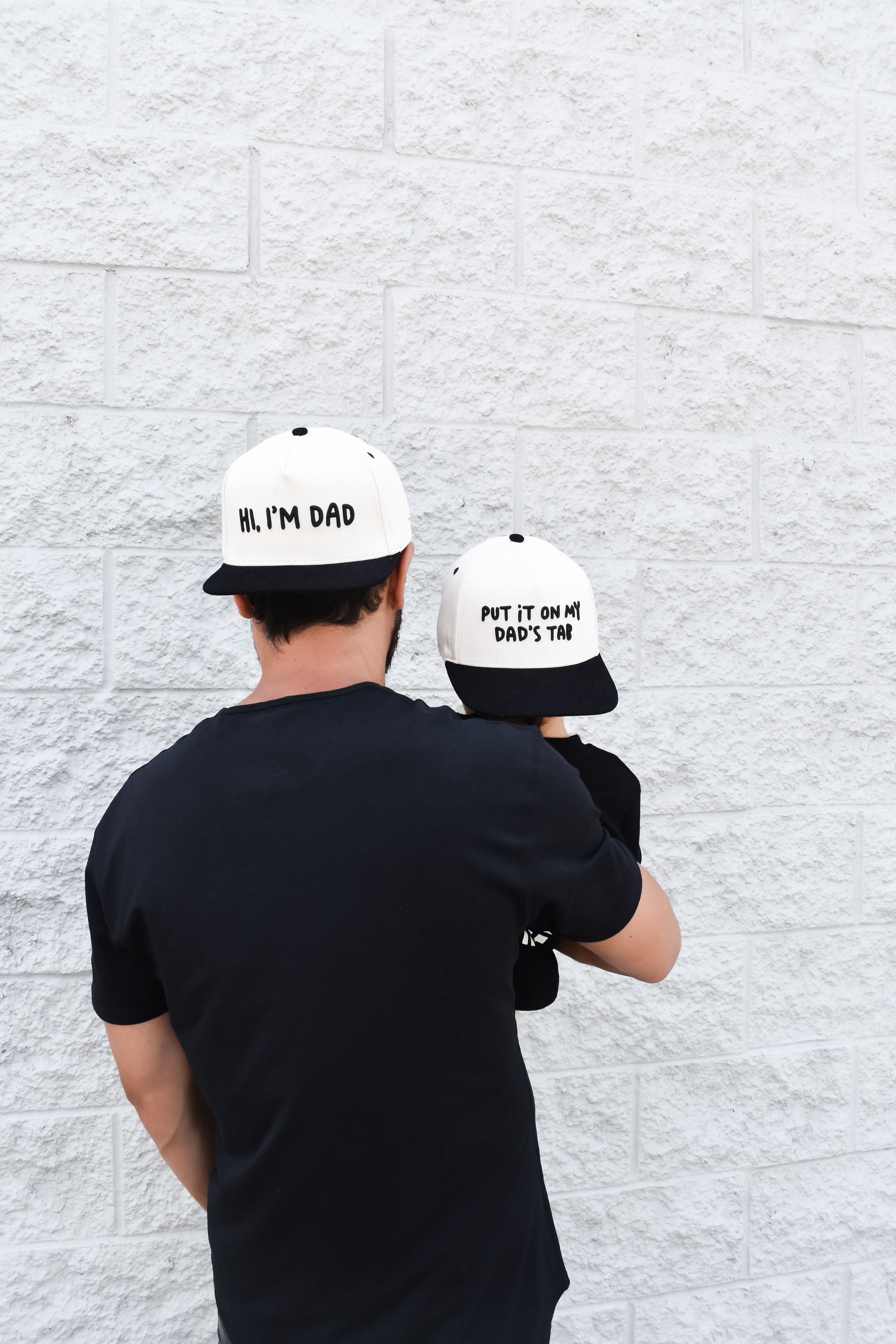 Dad wearing Hi, I’m Dad snapback outdoors while spending time with child.