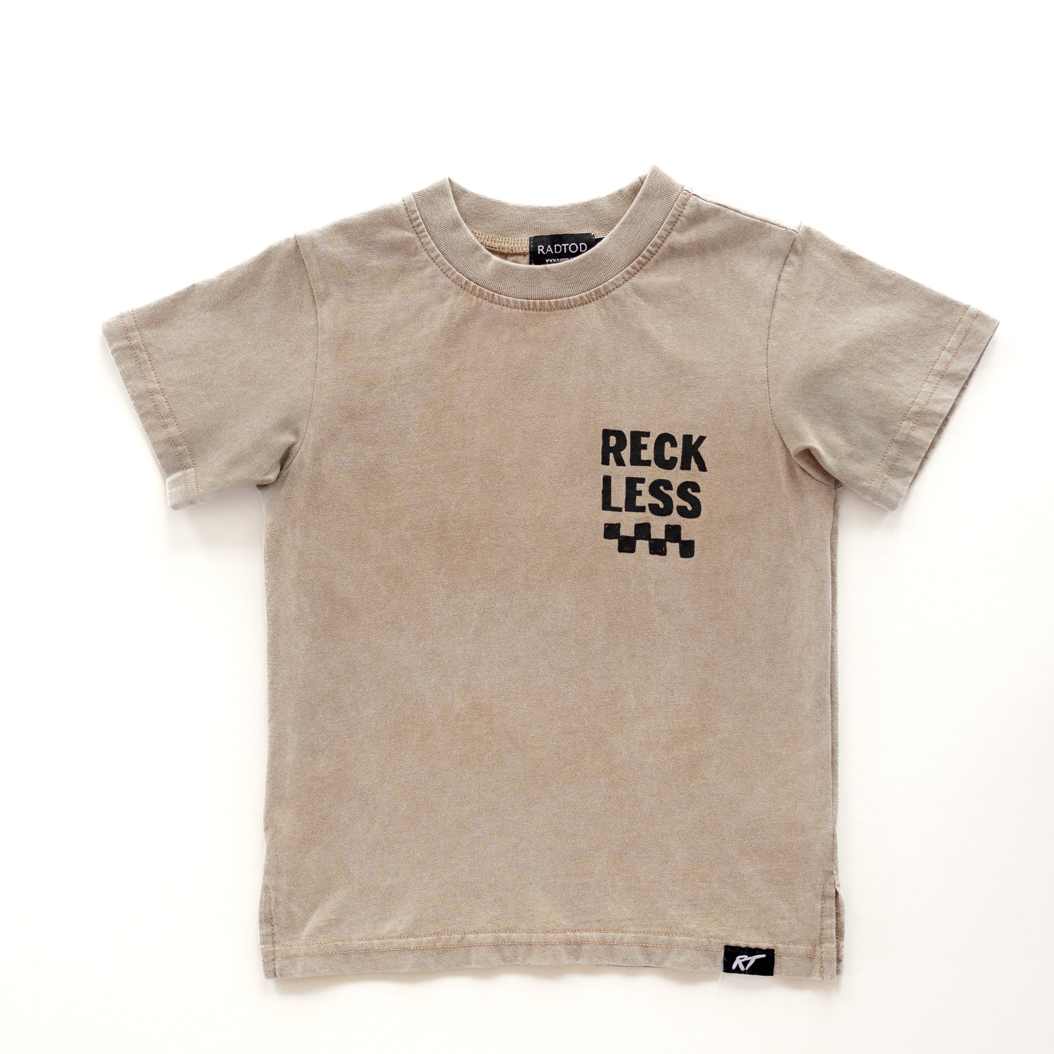 front side Beige acid wash toddler tee with bold 'Reckless' text, checkered patterns, and a smiley face graphic.