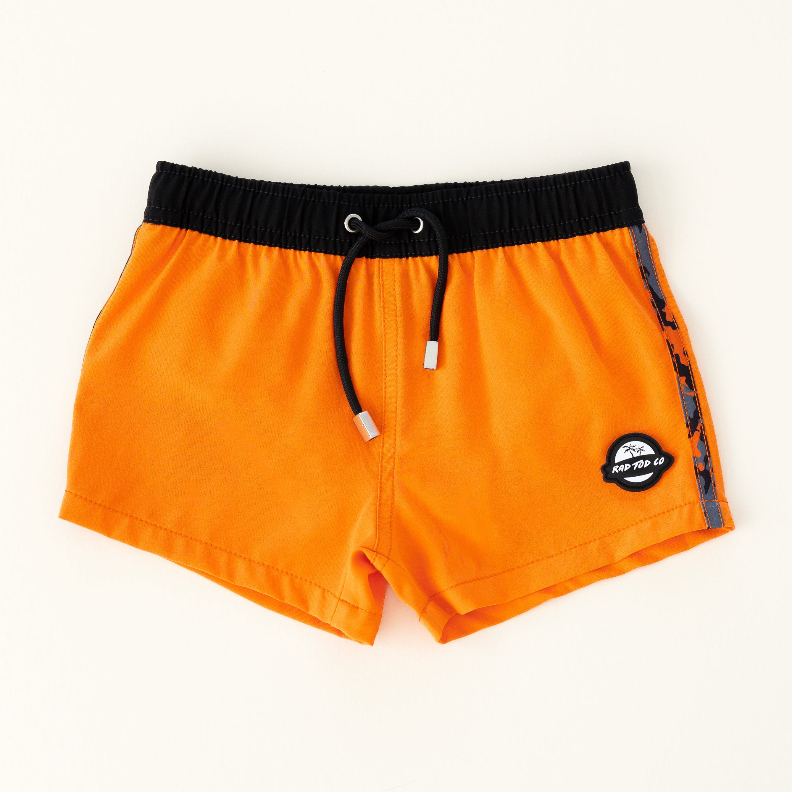 Bright orange with camo sides swim shorts with an elastic waistband and drawstring, made from quick-drying fabric. Ideal for swimming, beach trips, and outdoor activities. Features vibrant patterns and a comfortable fit for active kids.