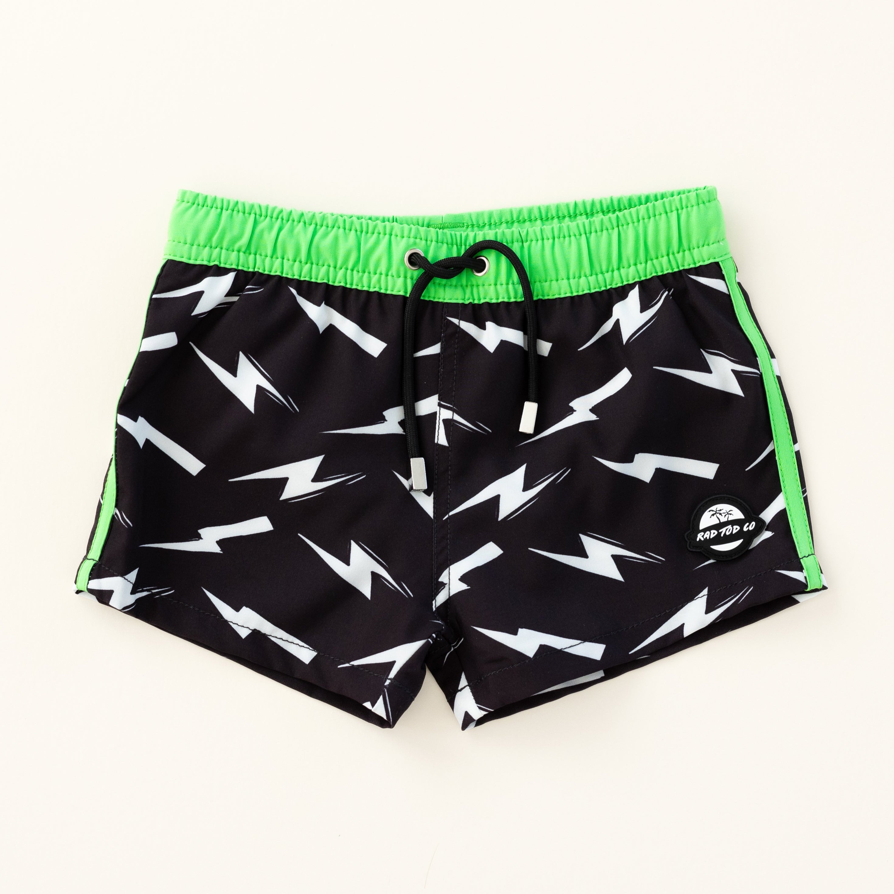 Bright thunderbolt pattern swim shorts with an elastic waistband and drawstring, made from quick-drying fabric. Ideal for swimming, beach trips, and outdoor activities. Features vibrant patterns and a comfortable fit for active kids.