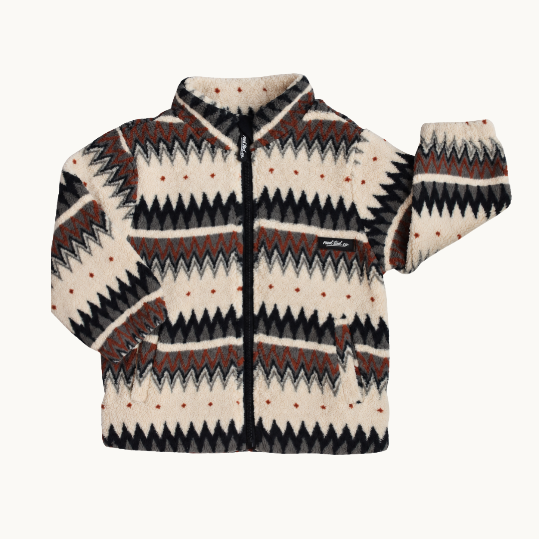 A fleece zip-up jacket with a geometric Fair Isle pattern in cream, black, and rust brown, shown against a plain off-white background.