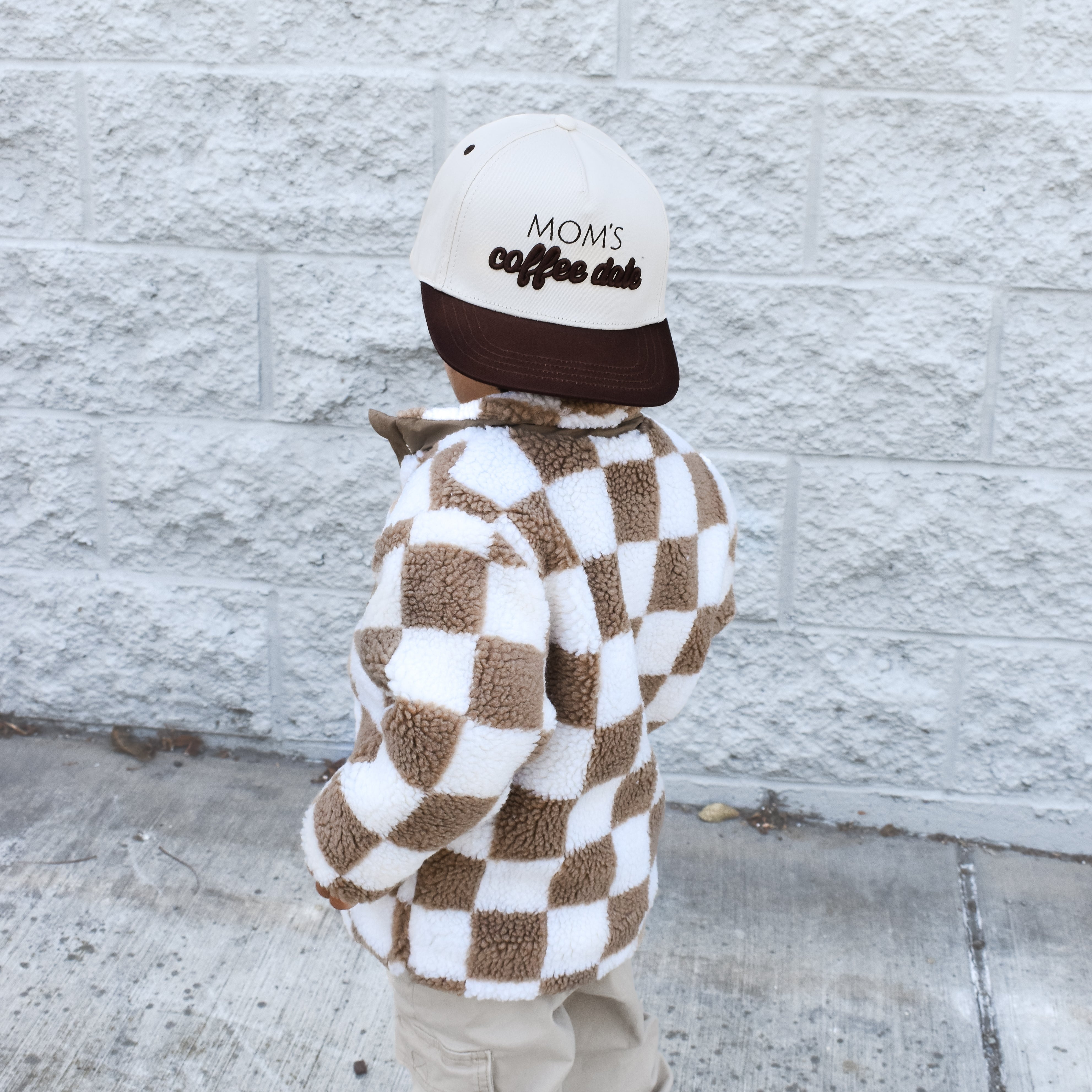 Child wearing the Moms Coffee Date snapback while playing outdoors.