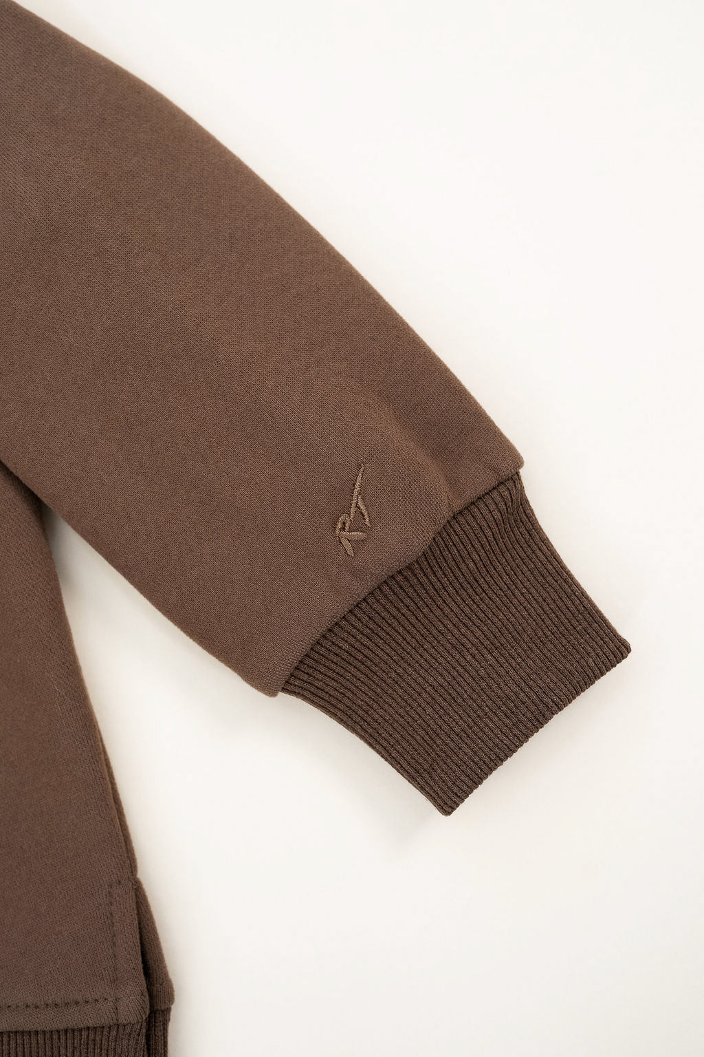 Brown jacket sleeve with a small logo on a white background