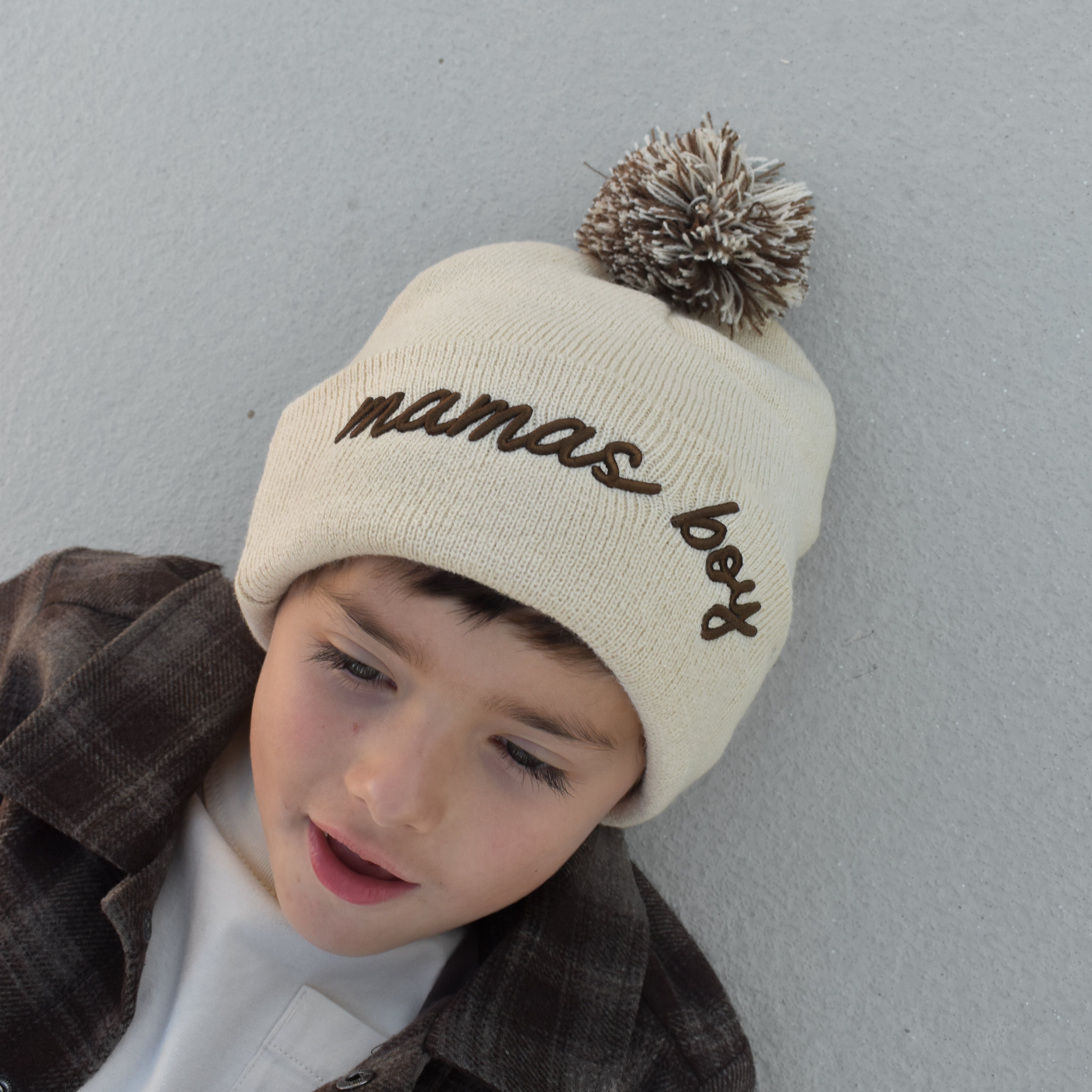 Toddler wearing beige Mamas Boy beanie with brown lettering