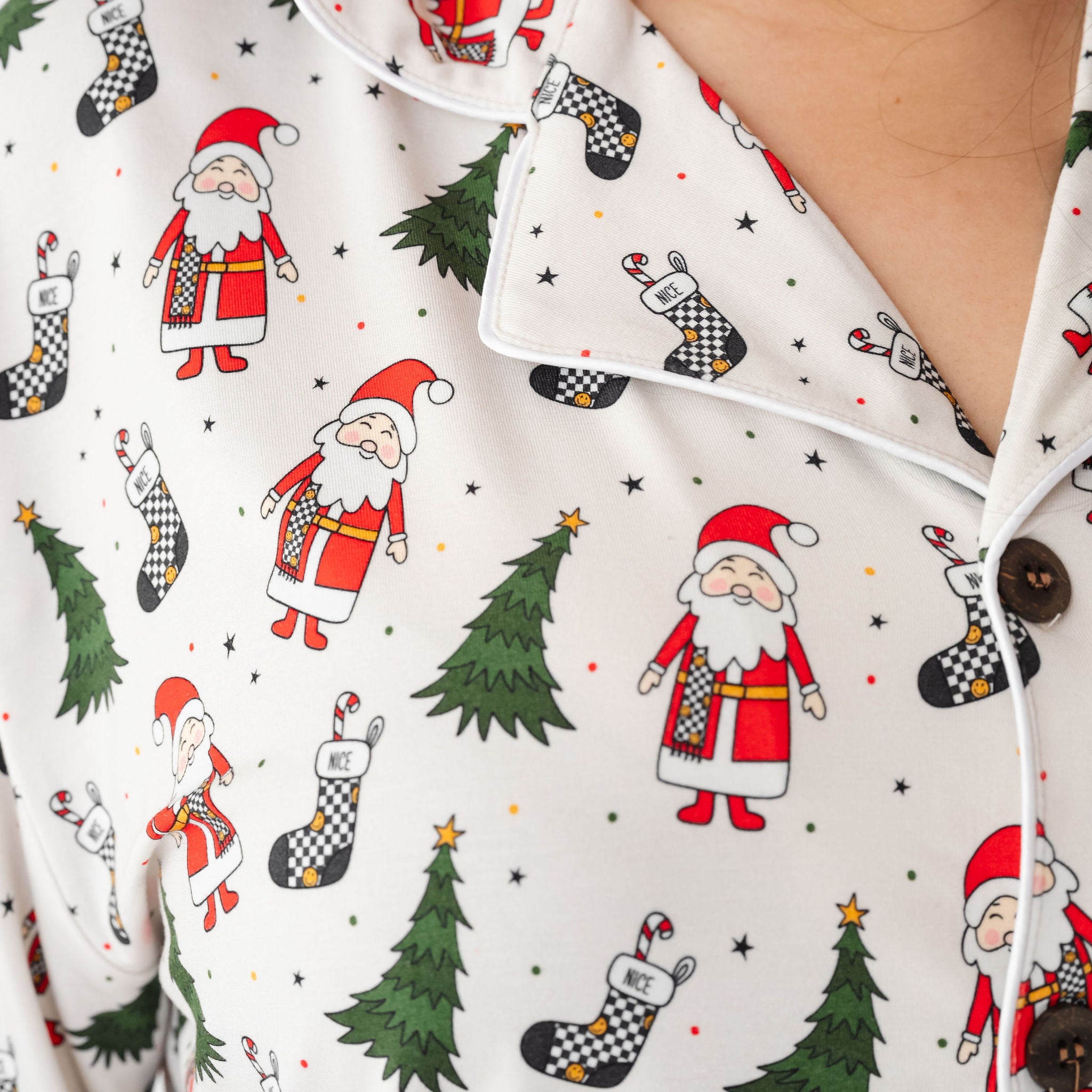 Close-up of a shirt with Christmas-themed pattern featuring Santa Claus, trees, and stockings by RAd toddler