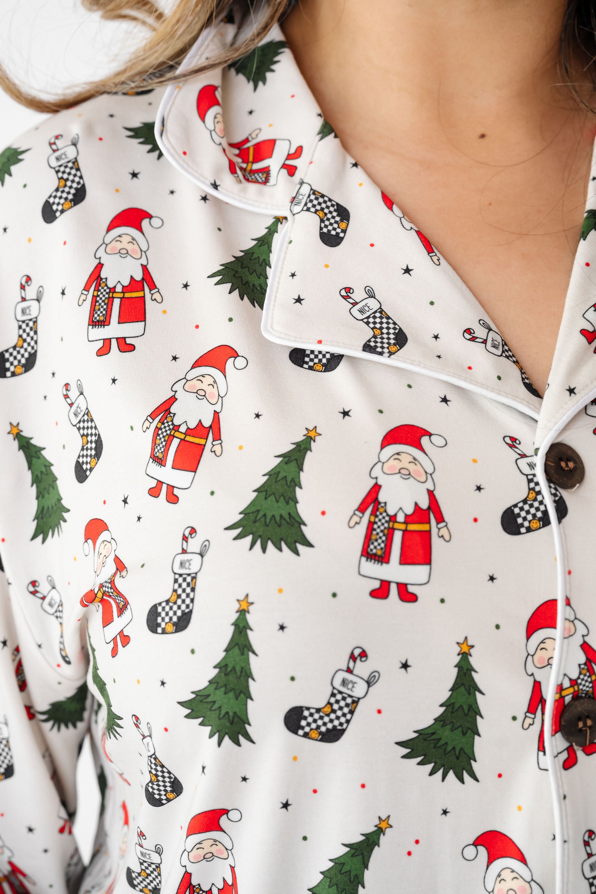 Close-up of a shirt with Christmas-themed pattern featuring Santa Claus, trees, and stockings by RAd toddler