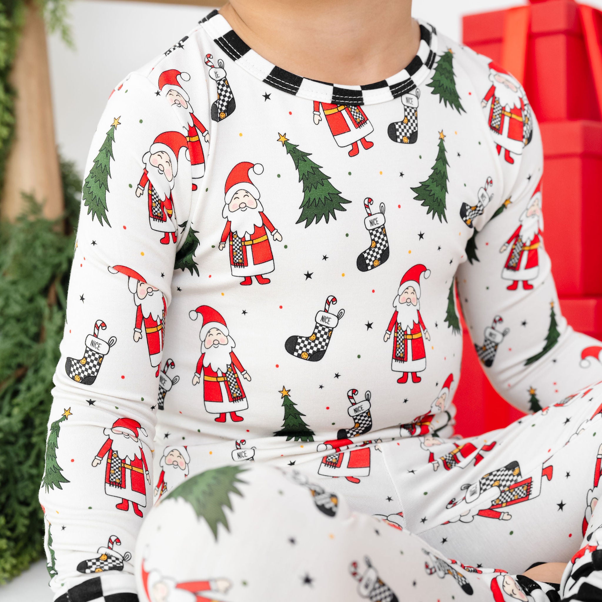 Child wearing Christmas-themed pajamas with Santa Claus and trees by RAD TODDLER