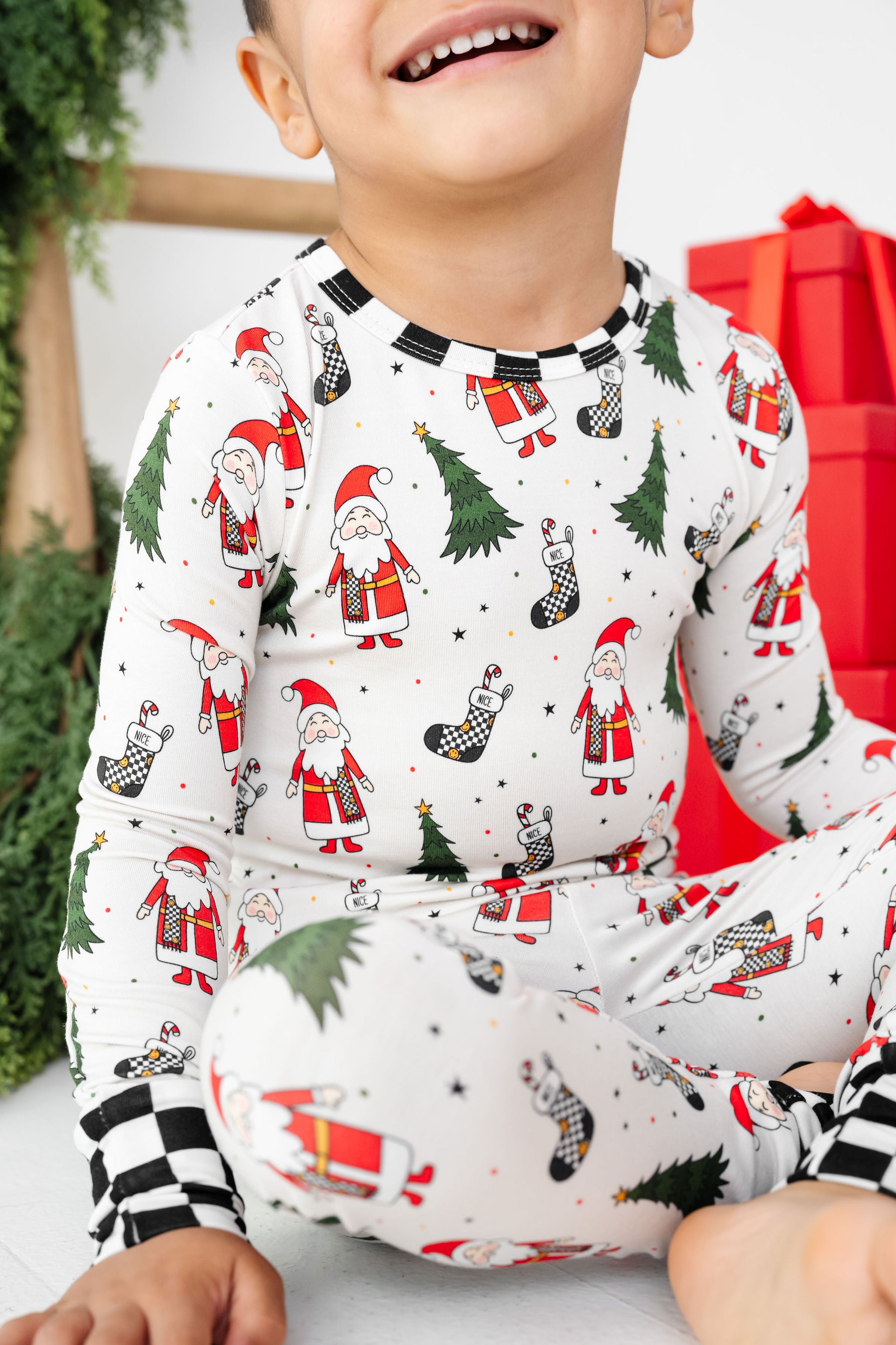 Child wearing Christmas-themed pajamas with Santa Claus and trees by RAD TODDLER