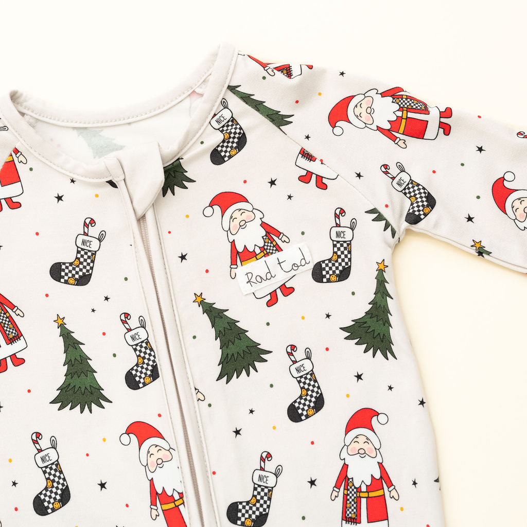 Baby onesie with Christmas-themed design featuring Santa Claus, trees, and stockings on a white background by RAD TODDLER