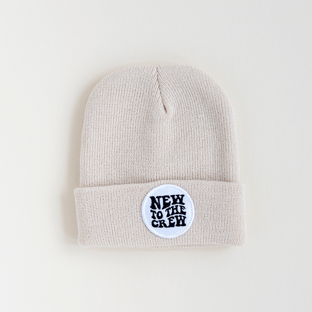 Beige beanie with a 'NEW TO THE CREW' patch on the front and RAD TOD logo at the back.