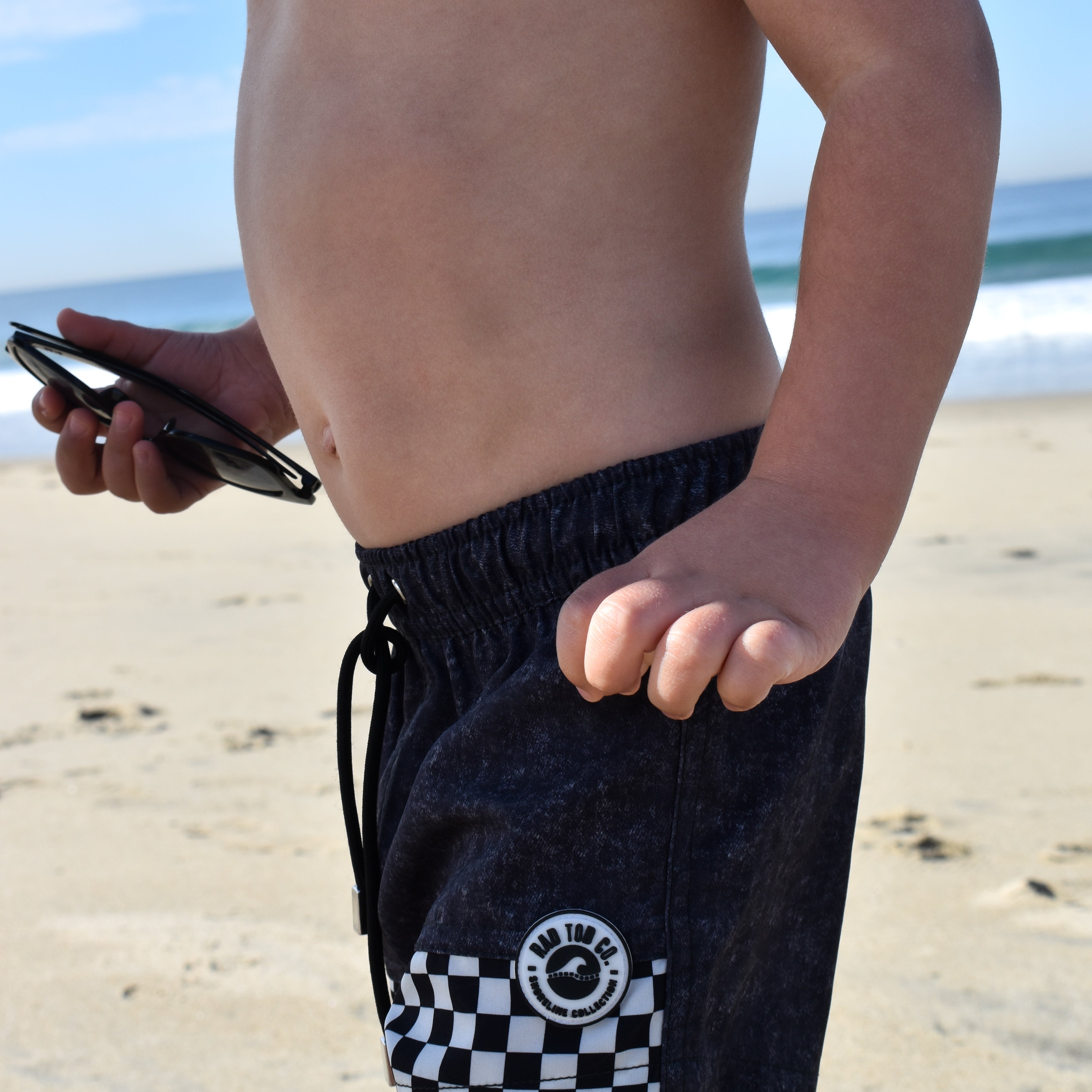 Child wearing Onyx Swimmie black checker swimsuit at the beach
