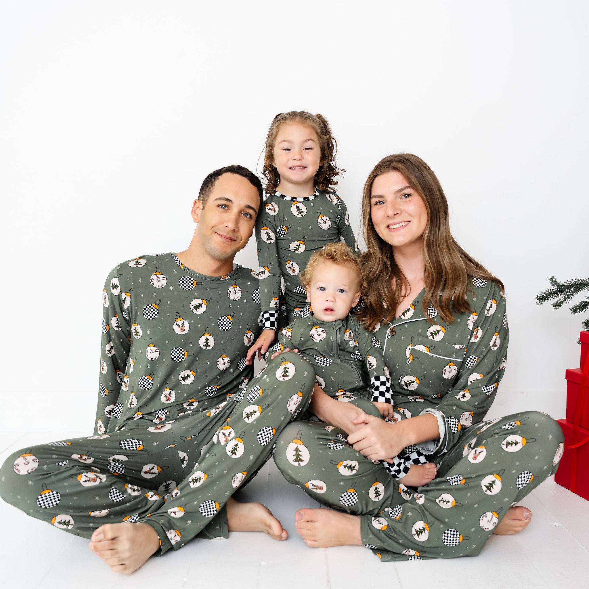 Family of four wearing matching green pajamas with a Christmas tree pattern on a white background by RAD TODDLER