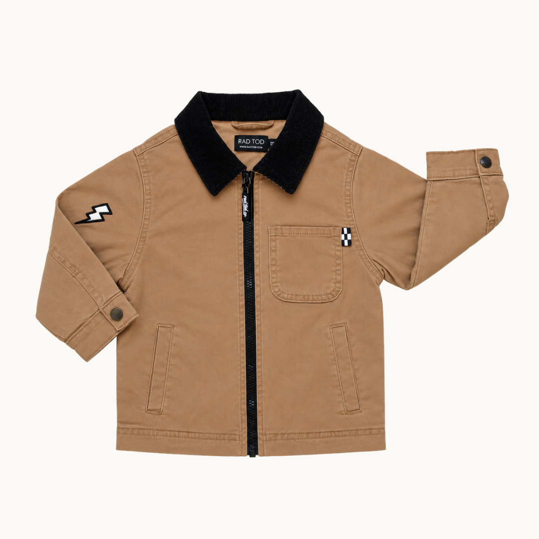 A toddler's tan canvas utility jacket with a black fleece collar, black zipper, and small black-and-white checkered accents on the chest and sleeve, shown flat on a light cream background.