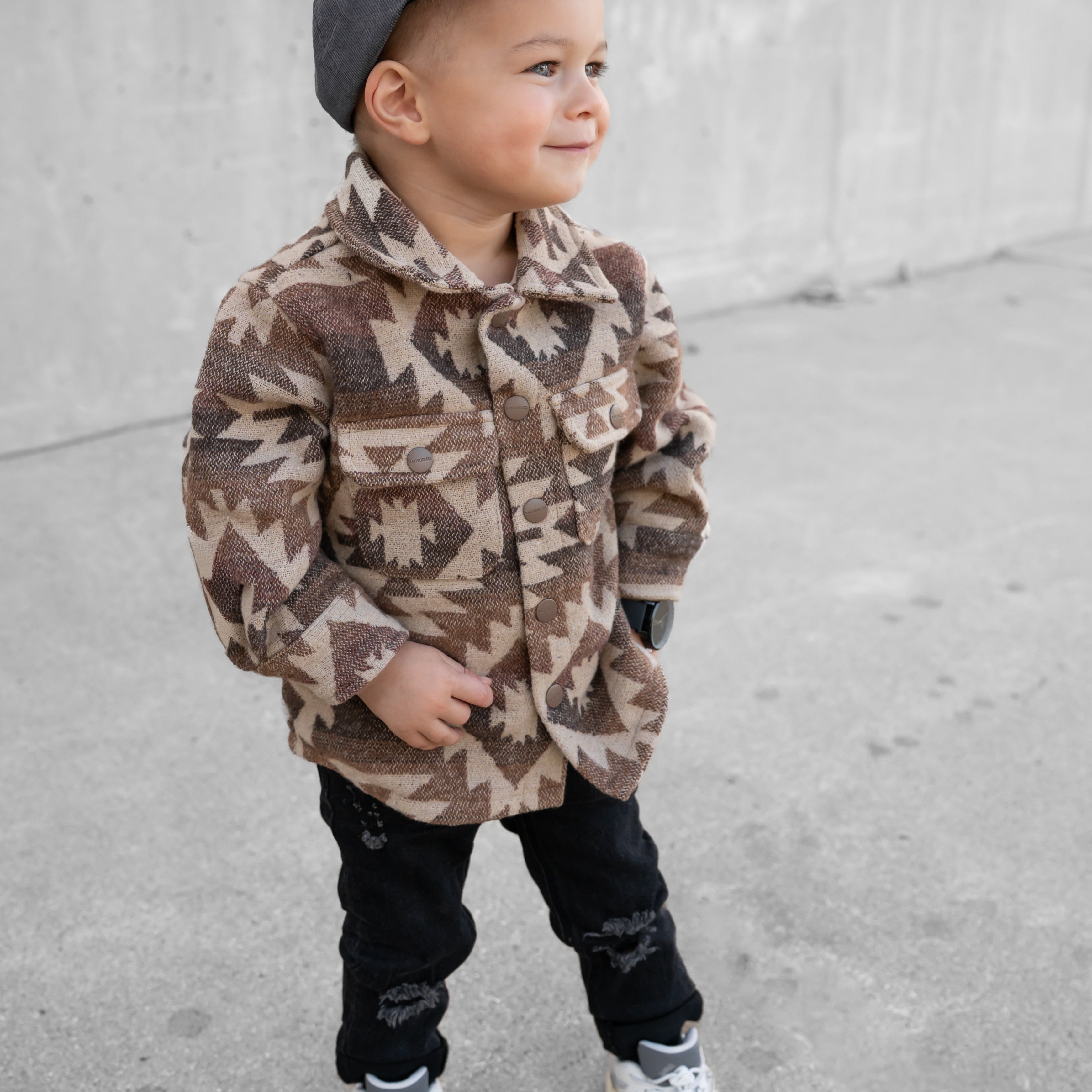 Child wearing RAD TODDLER Skate Club snapback outdoors while playing.