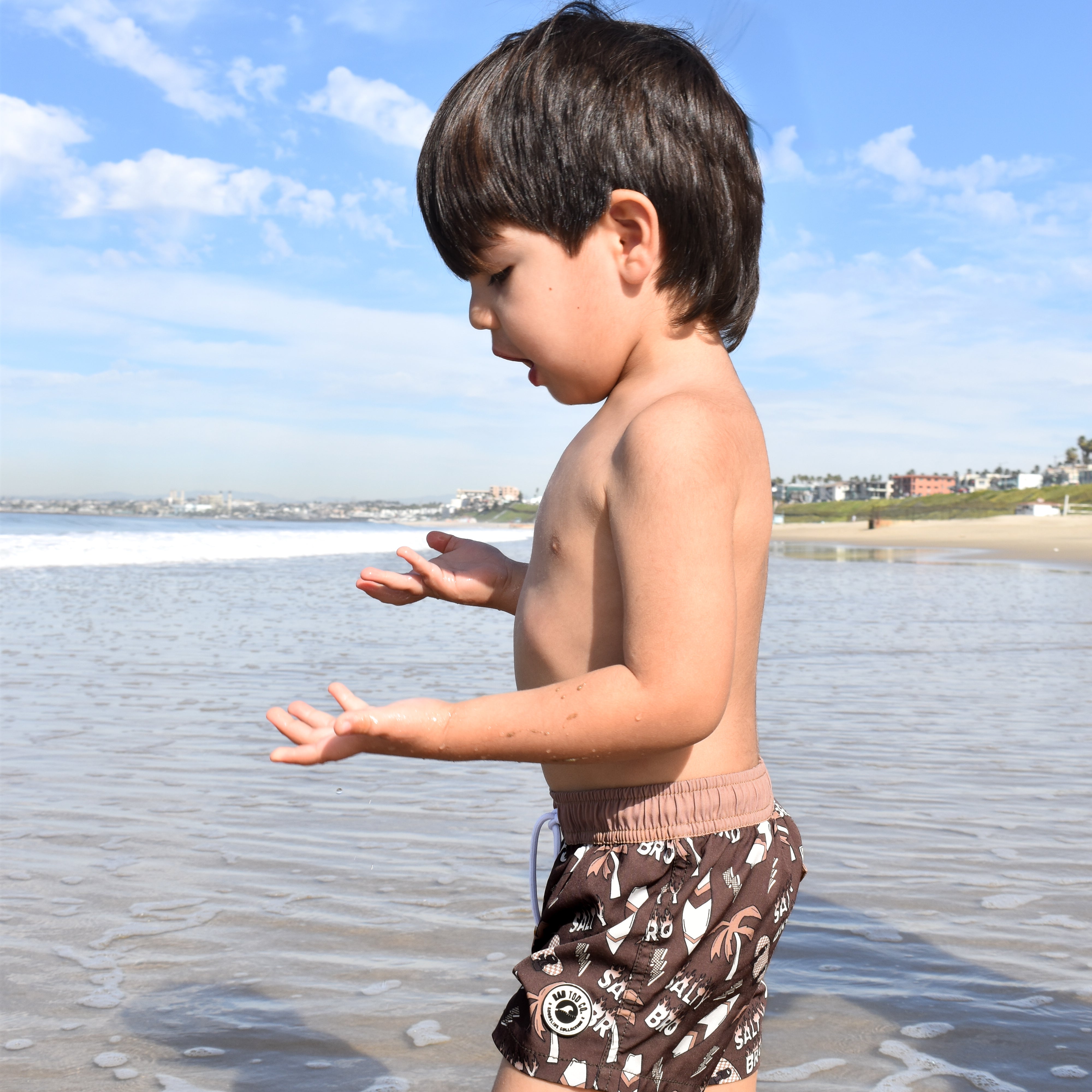 Toddler wearing Salty Bro Shorts in brown with surf-inspired graphics