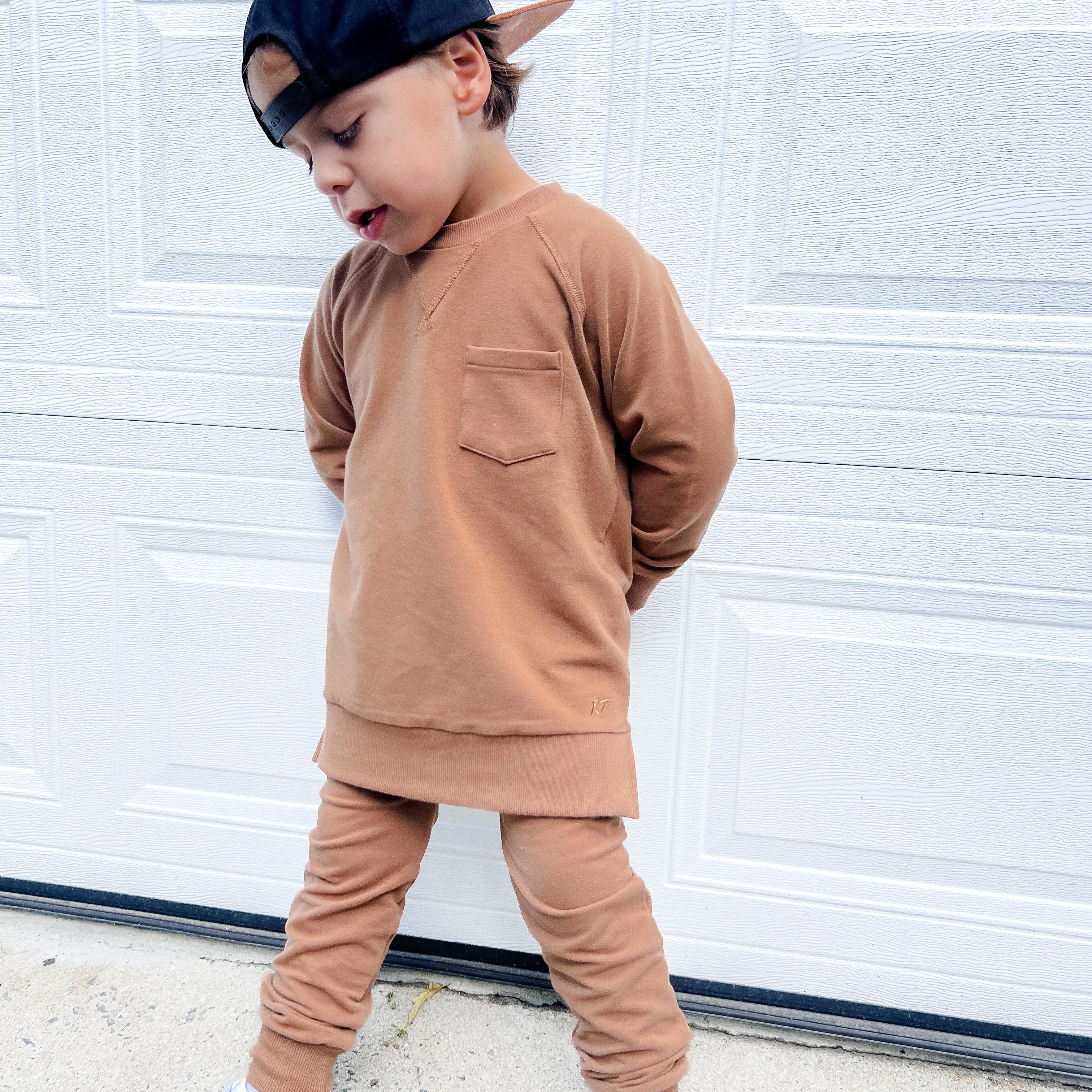 Young boy wearing almond Core Collection toddler crewneck with oversized fit, standing outdoors.