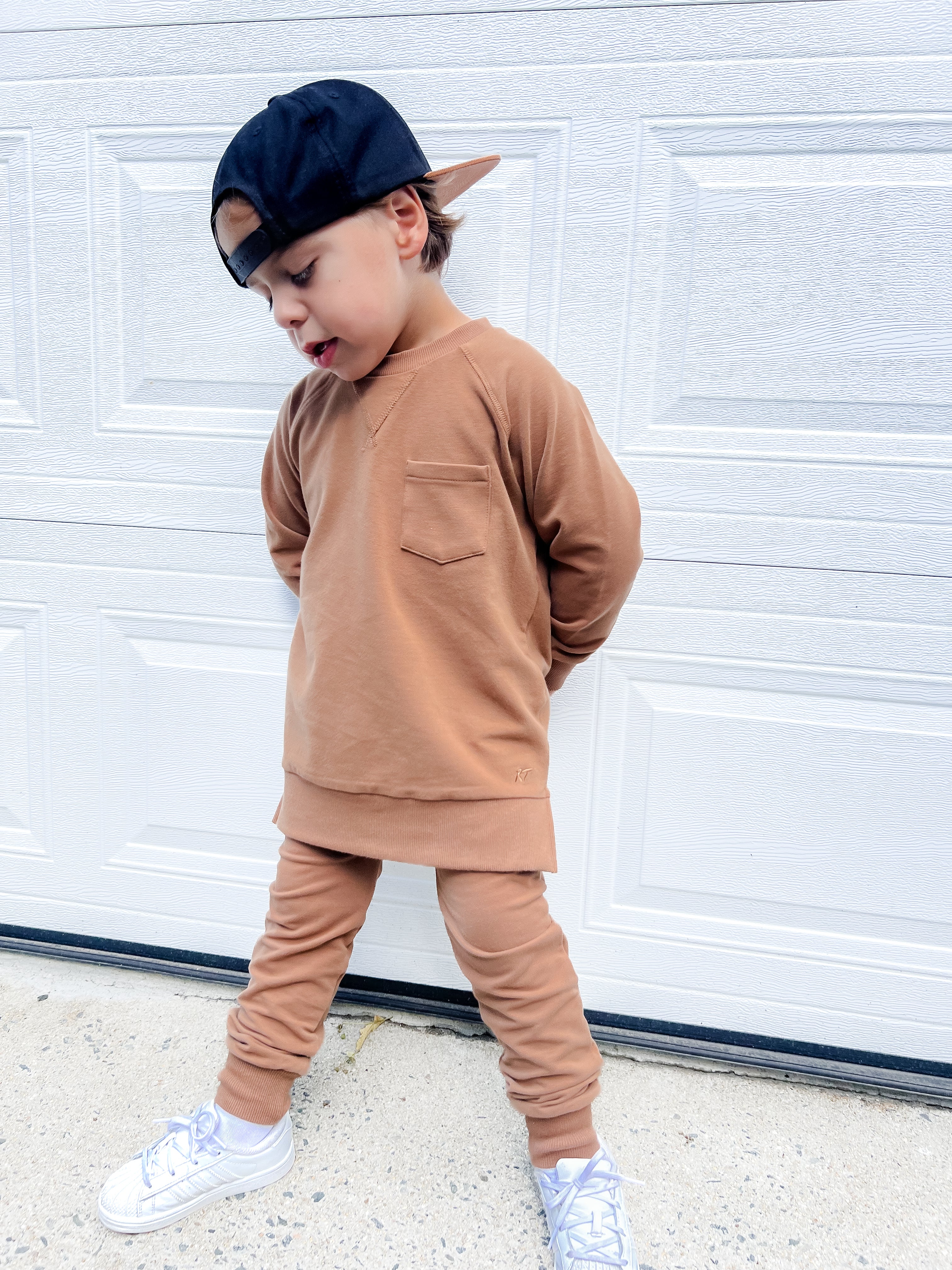 Young boy wearing almond Core Collection toddler crewneck with oversized fit, standing outdoors.