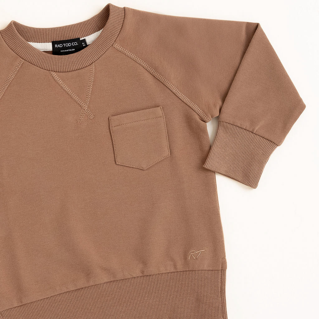 Flat lay of almond toddler crewneck from the Core Collection with oversized, boxy fit and RT embroidered logo.
