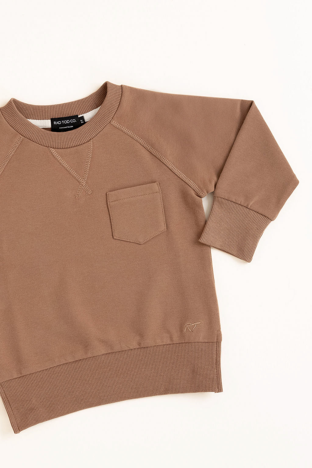 Flat lay of almond toddler crewneck from the Core Collection with oversized, boxy fit and RT embroidered logo.