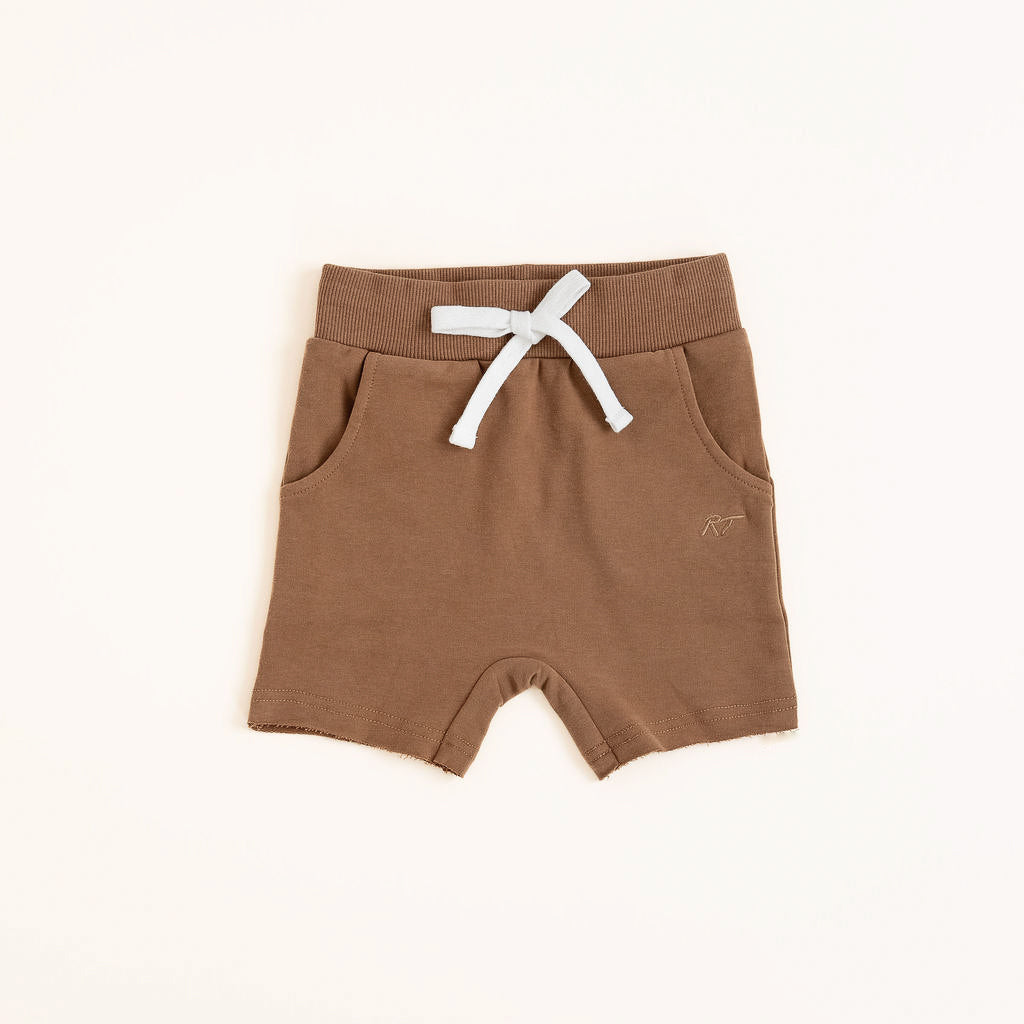 Flat lay of almond toddler shorts from the Core Collection with adjustable waistband and front pockets.
