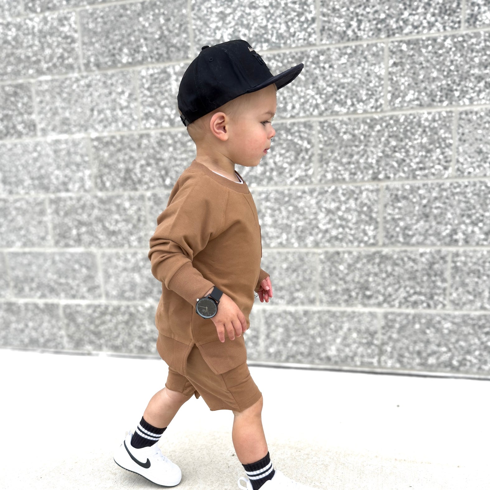 Young boy wearing almond Core Collection toddler set, standing outdoors and showcasing the relaxed, above-the-knee fit.