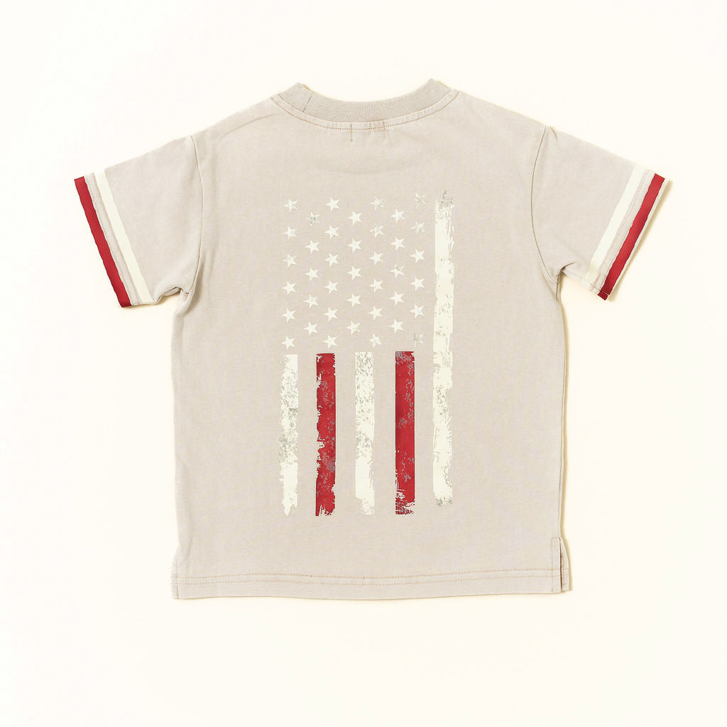 Beige t-shirt with American flag design on a white background by rad toddler