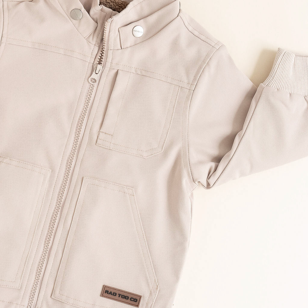 Beige children's jacket with a brand label on a light background