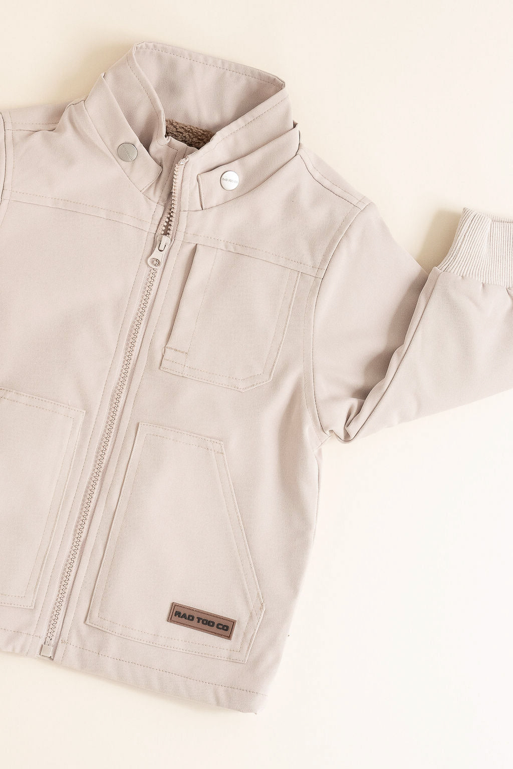 Beige children's jacket with a brand label on a light background
