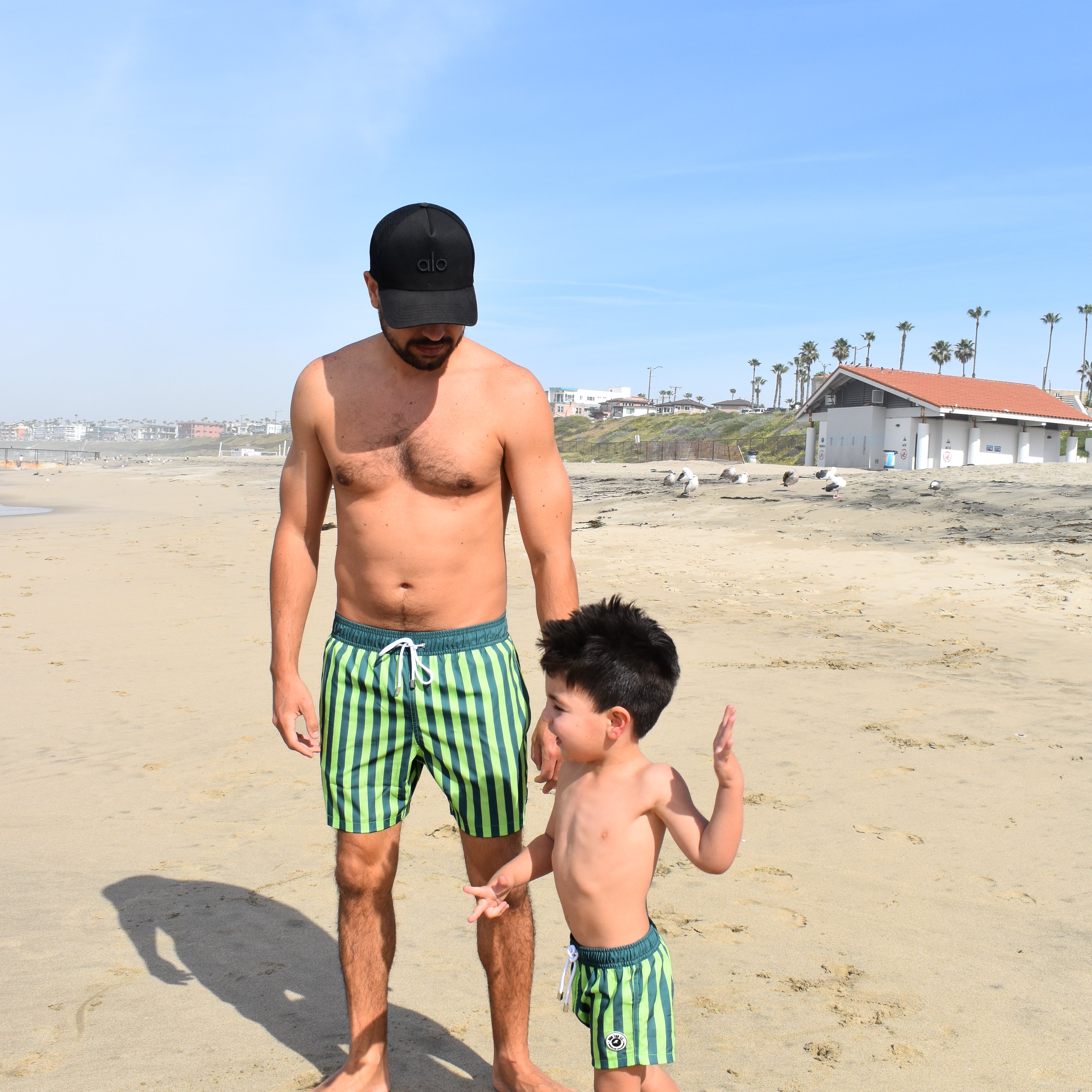 Man and child in matching lime green swim trunks on a beach