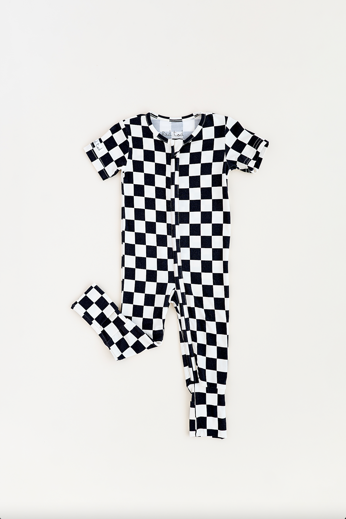 Black and white checkered bamboo short sleeve onesie for toddlers, featuring a two-way zipper and optional foldover footies by Rad Toddler.