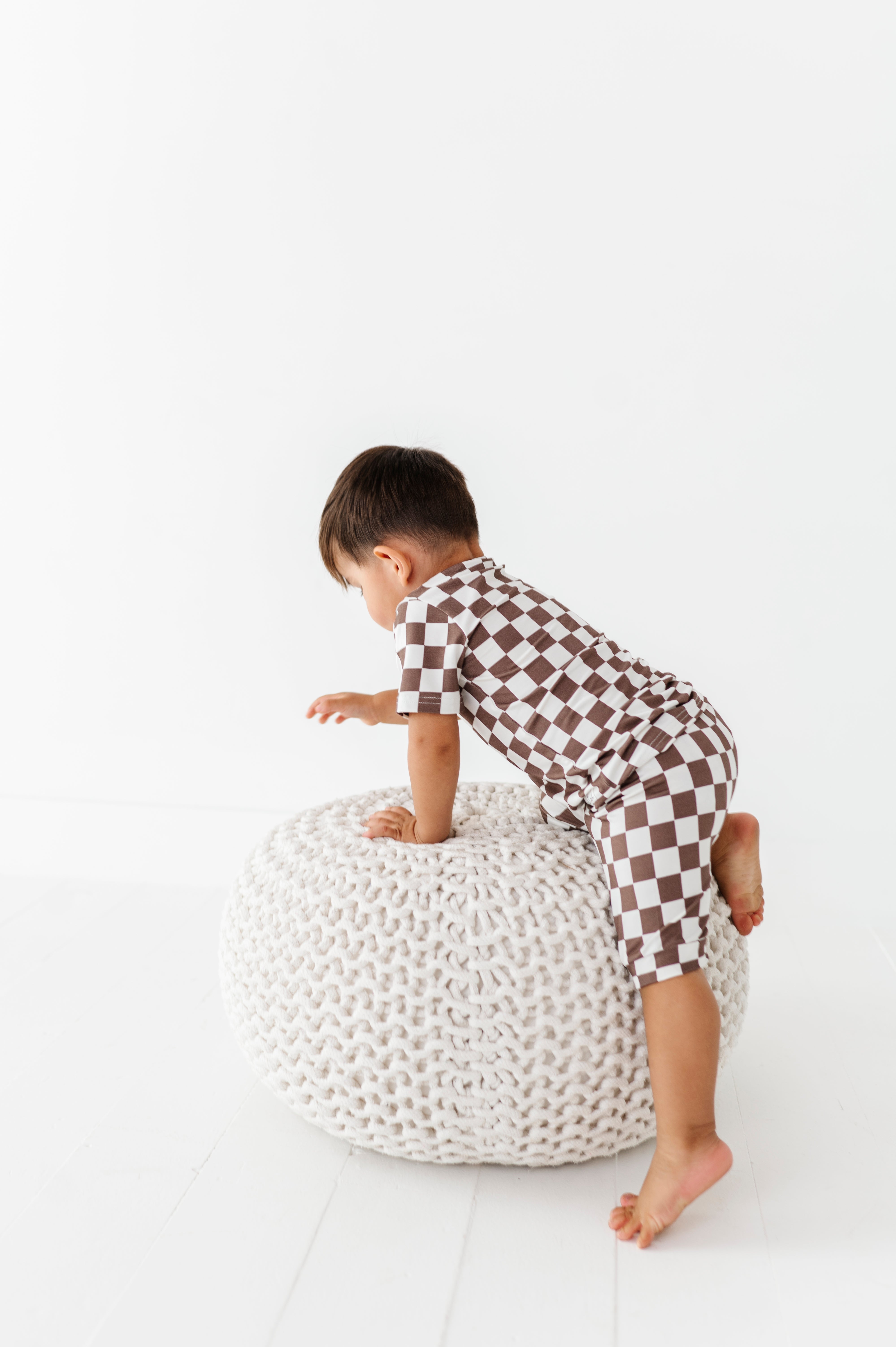 boy climbing wearing Bronze and white checkered bamboo short sleeve pajama set for toddlers, featuring soft, breathable fabric and a stretchy waistband by Rad Toddler.