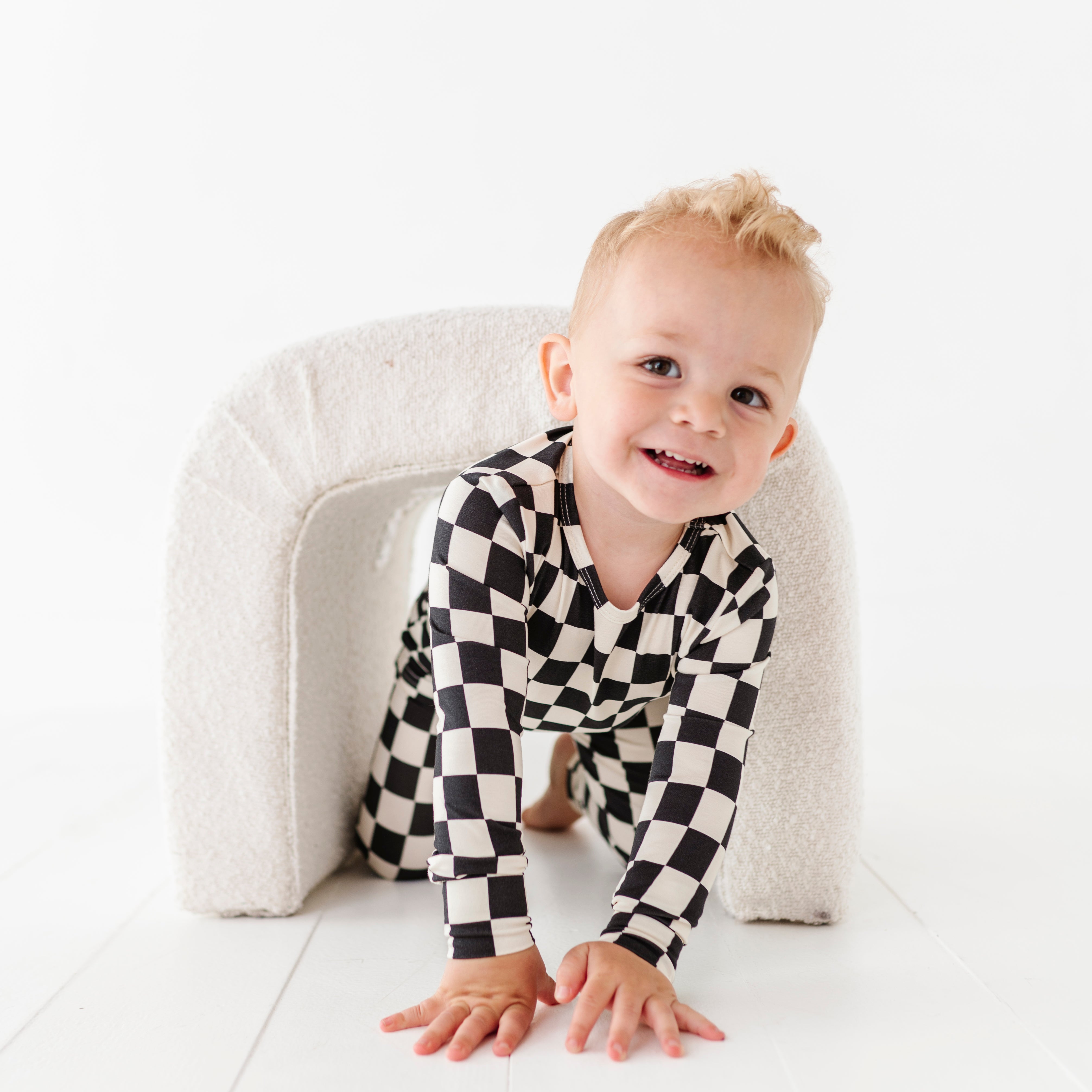 boy playing while wearing Black checkered 2-piece pajamas for toddlers and kids, featuring a comfy fit and elastic waistband by Rad Toddler.