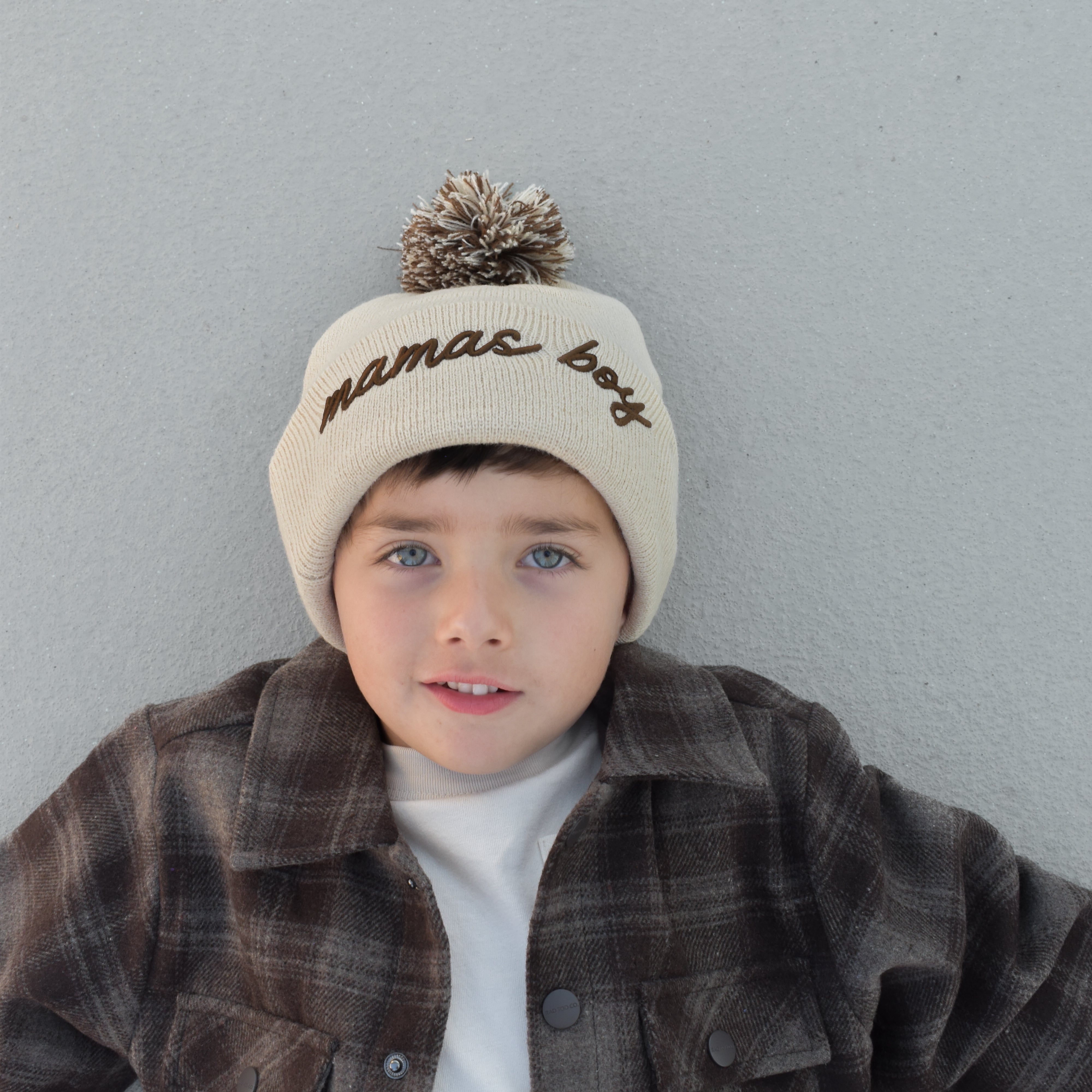 Toddler wearing beige Mamas Boy beanie with brown lettering