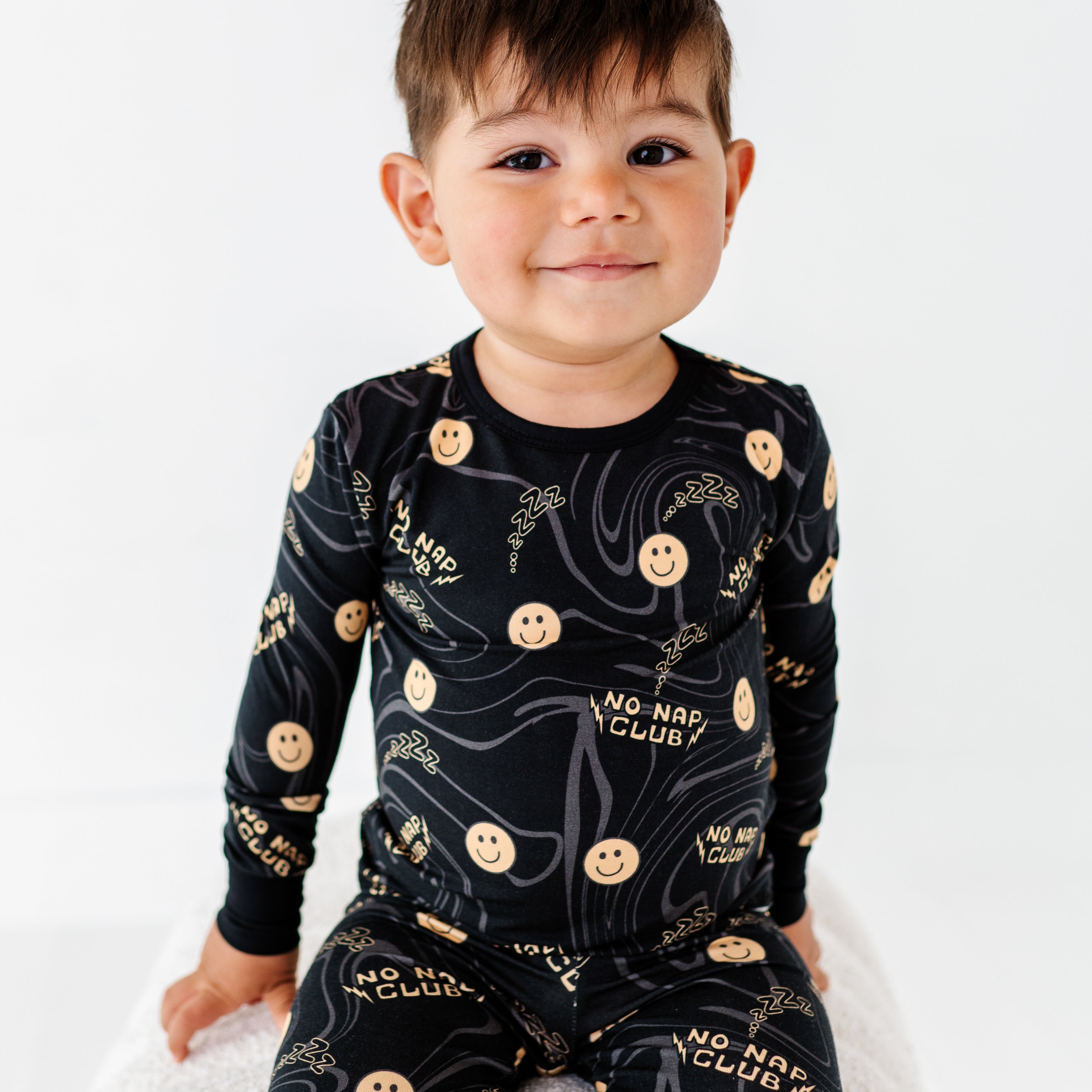 boy wearing Cute No Nap Club bamboo 2-piece set featuring smiley face graphics and a wavy pattern