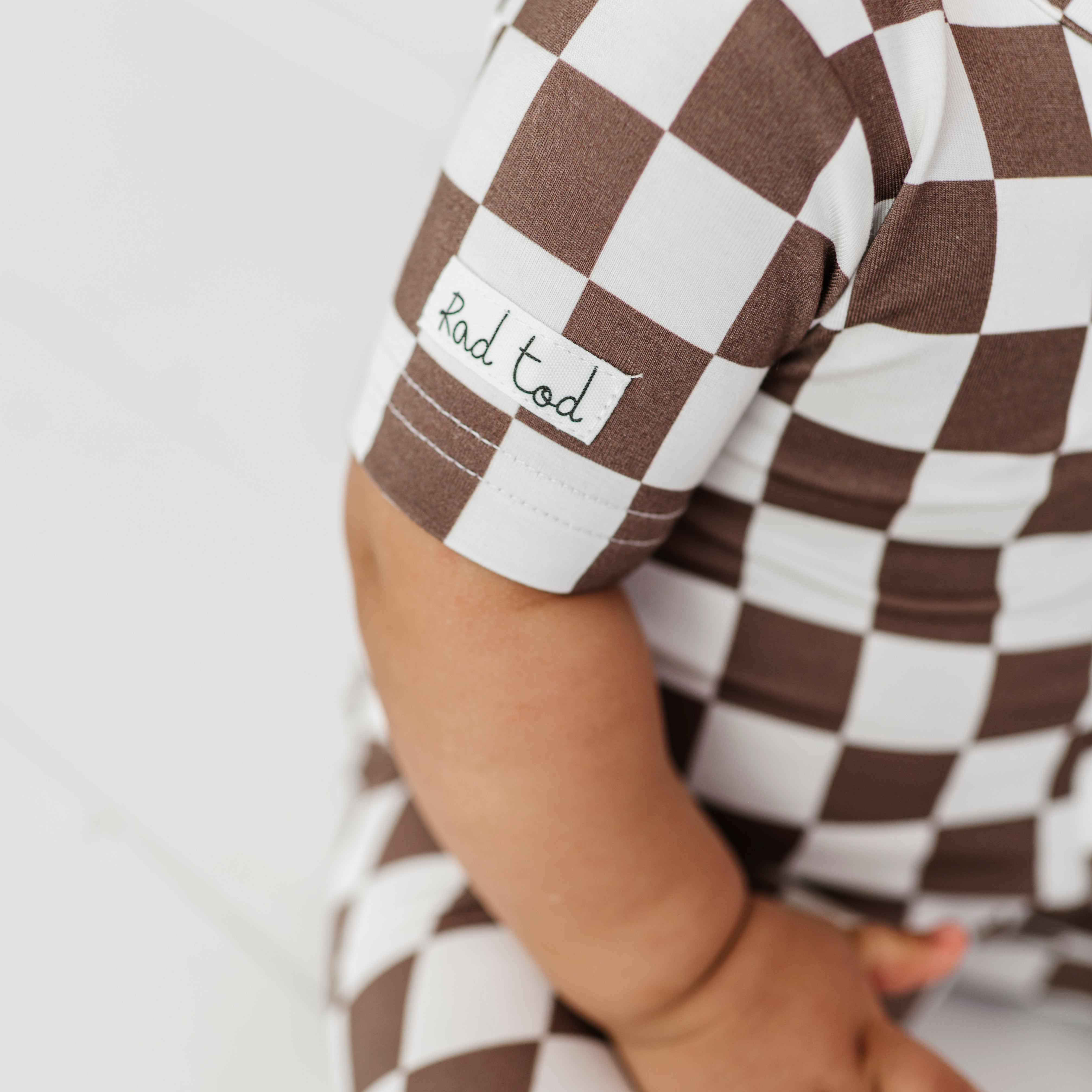 details on Bronze and white checkered bamboo onesie for toddlers, featuring a two-way zipper and optional foldover footies by Rad Toddler.
