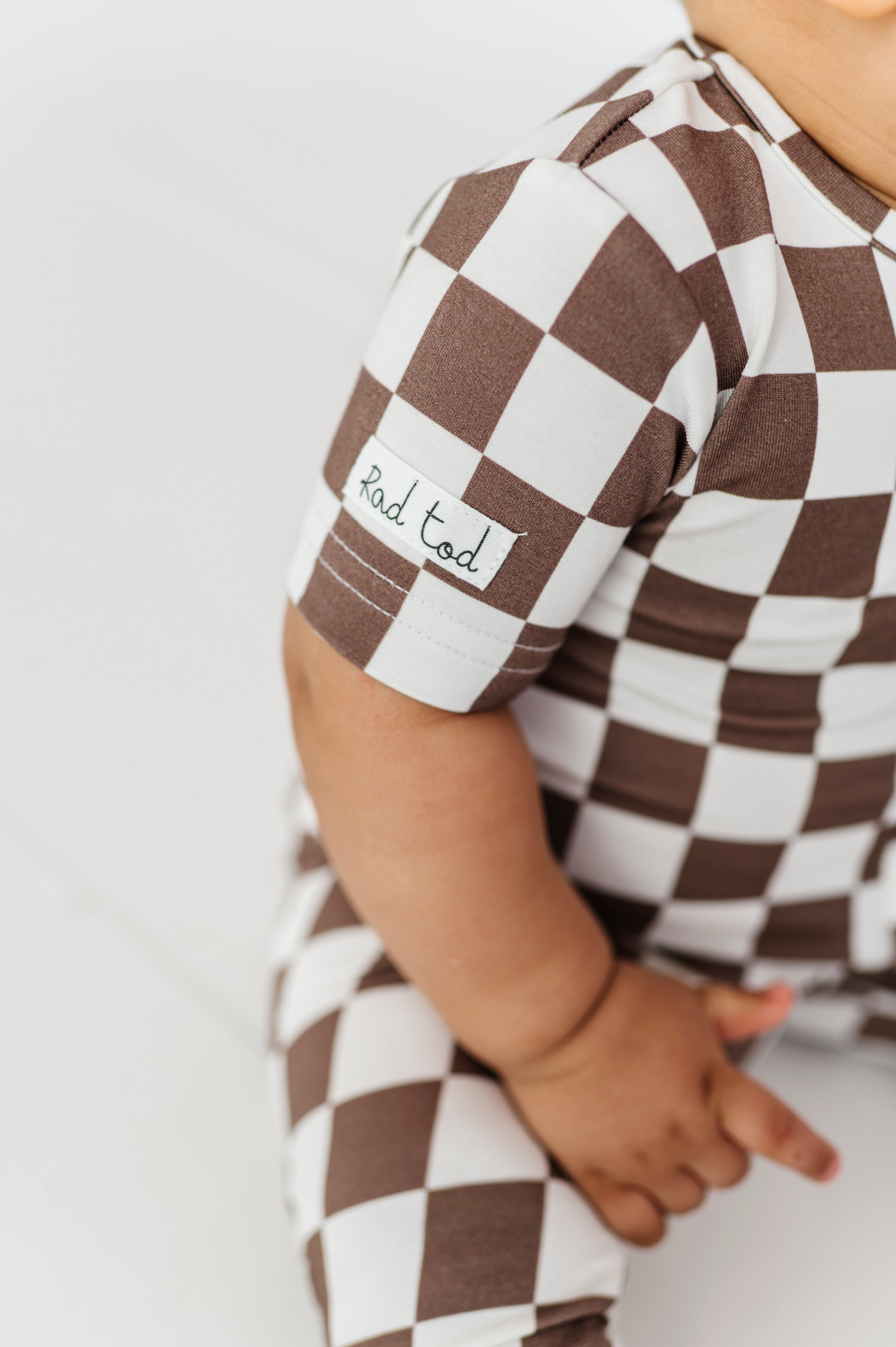 details on Bronze and white checkered bamboo onesie for toddlers, featuring a two-way zipper and optional foldover footies by Rad Toddler.