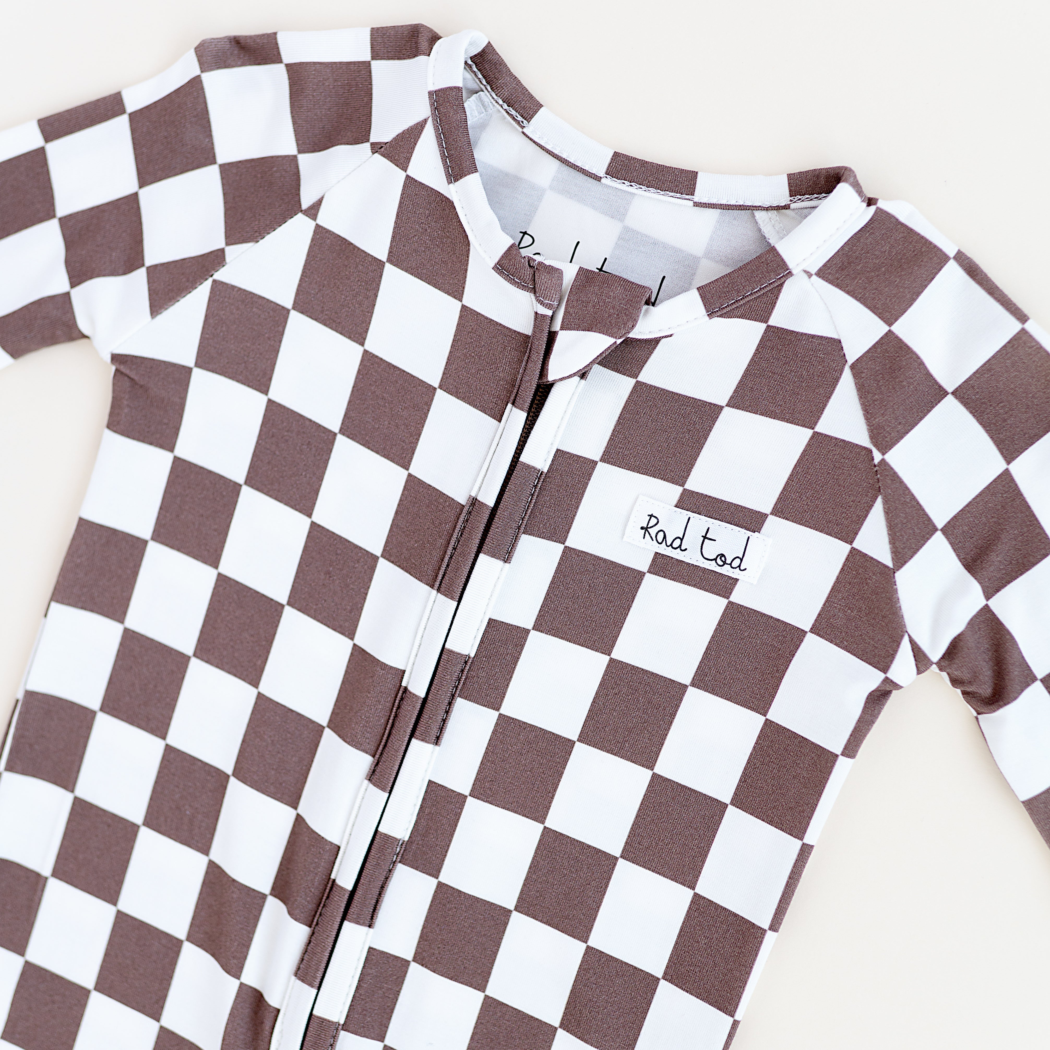 details Bronze and white checkered bamboo pajamas for toddlers, featuring a two-way zipper and foldover footies by Rad Toddler.
