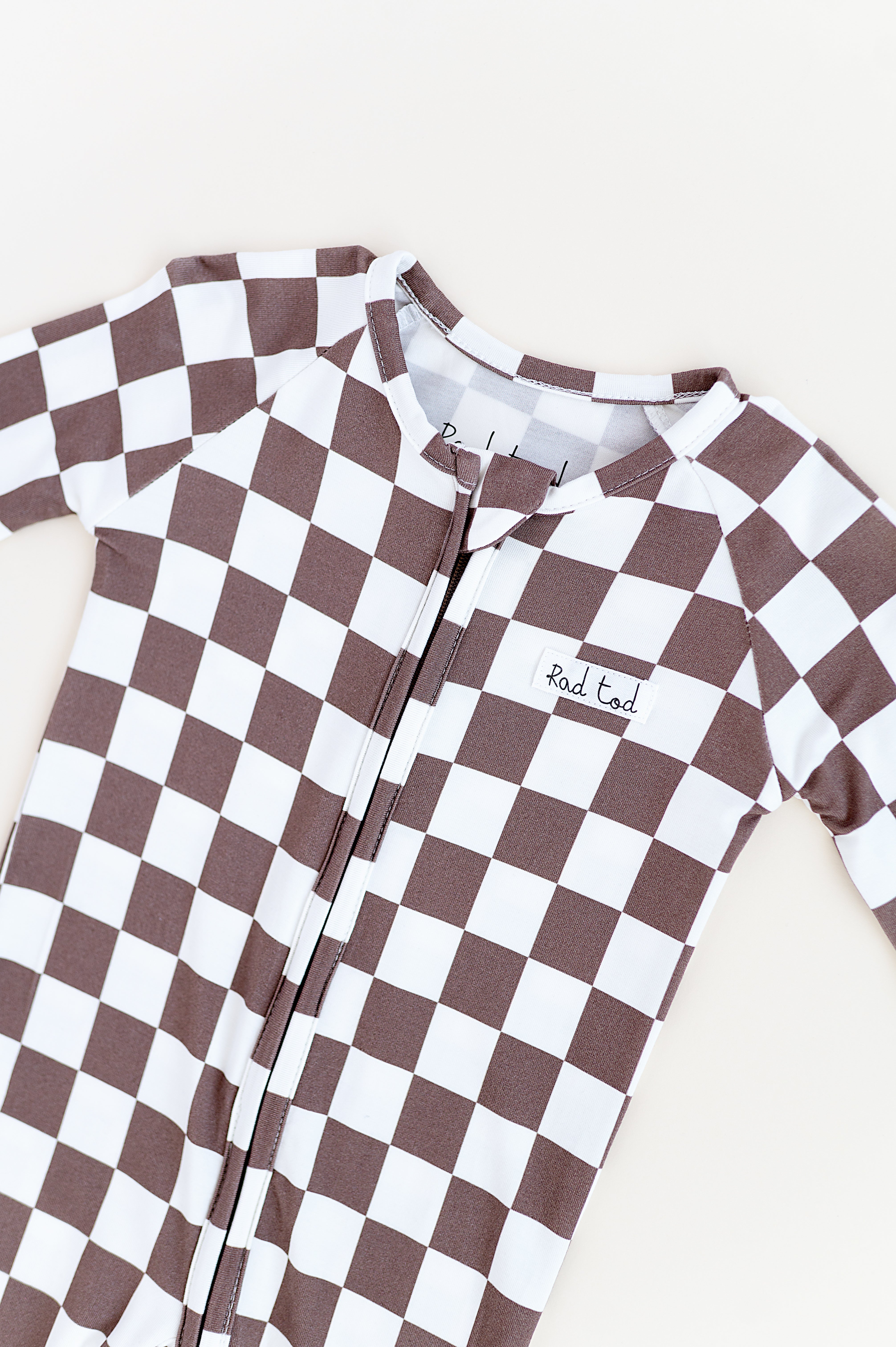 details Bronze and white checkered bamboo pajamas for toddlers, featuring a two-way zipper and foldover footies by Rad Toddler.