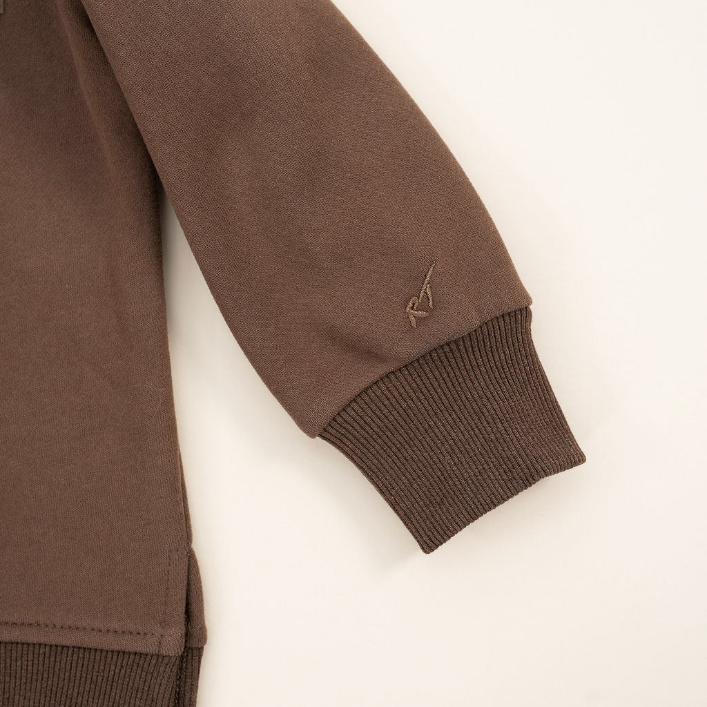 details  on Brown “Mama’s Boy” crewneck with slightly lighter brown lettering, laid flat on a neutral background.