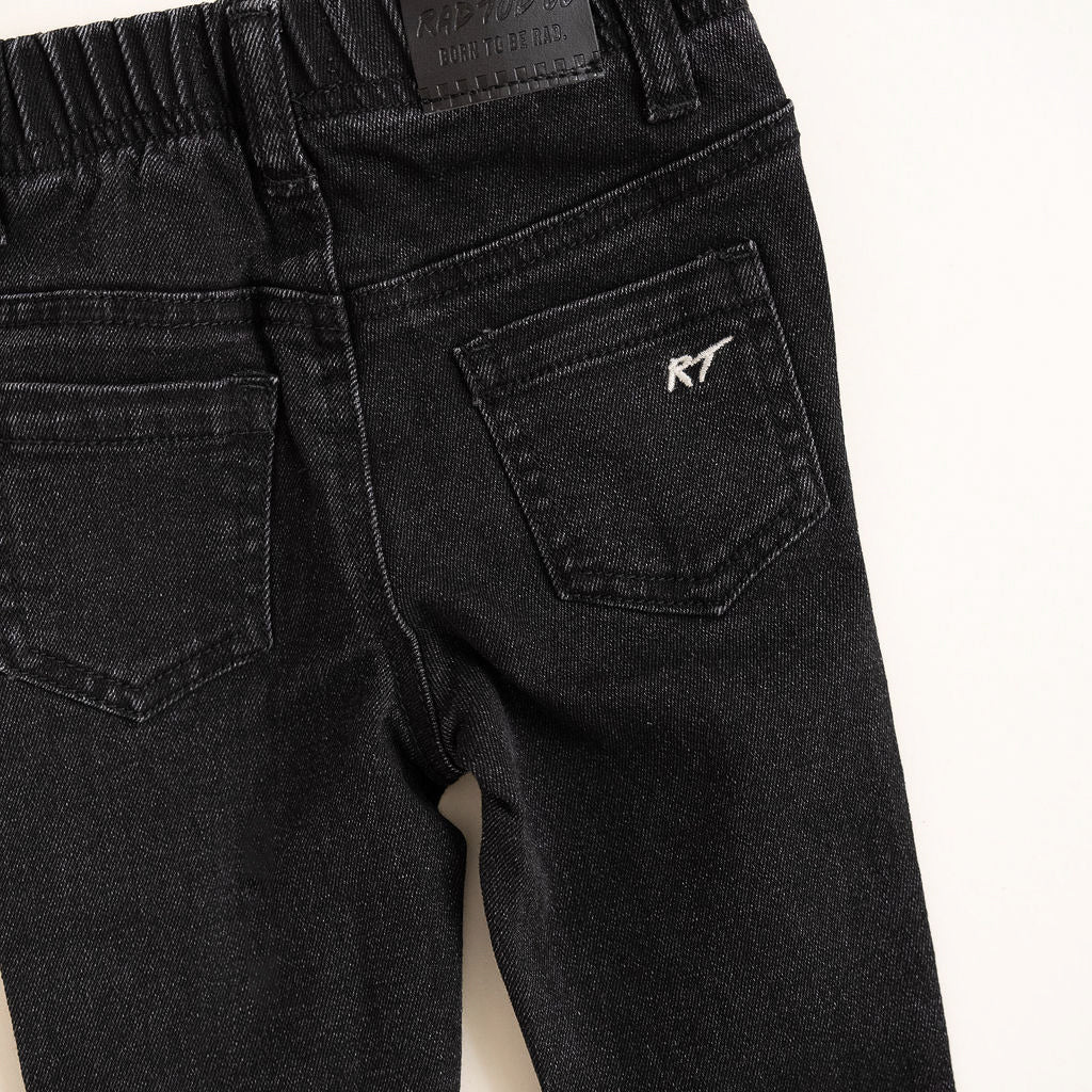 Black jeans with a brand logo on the back pocket against a white background