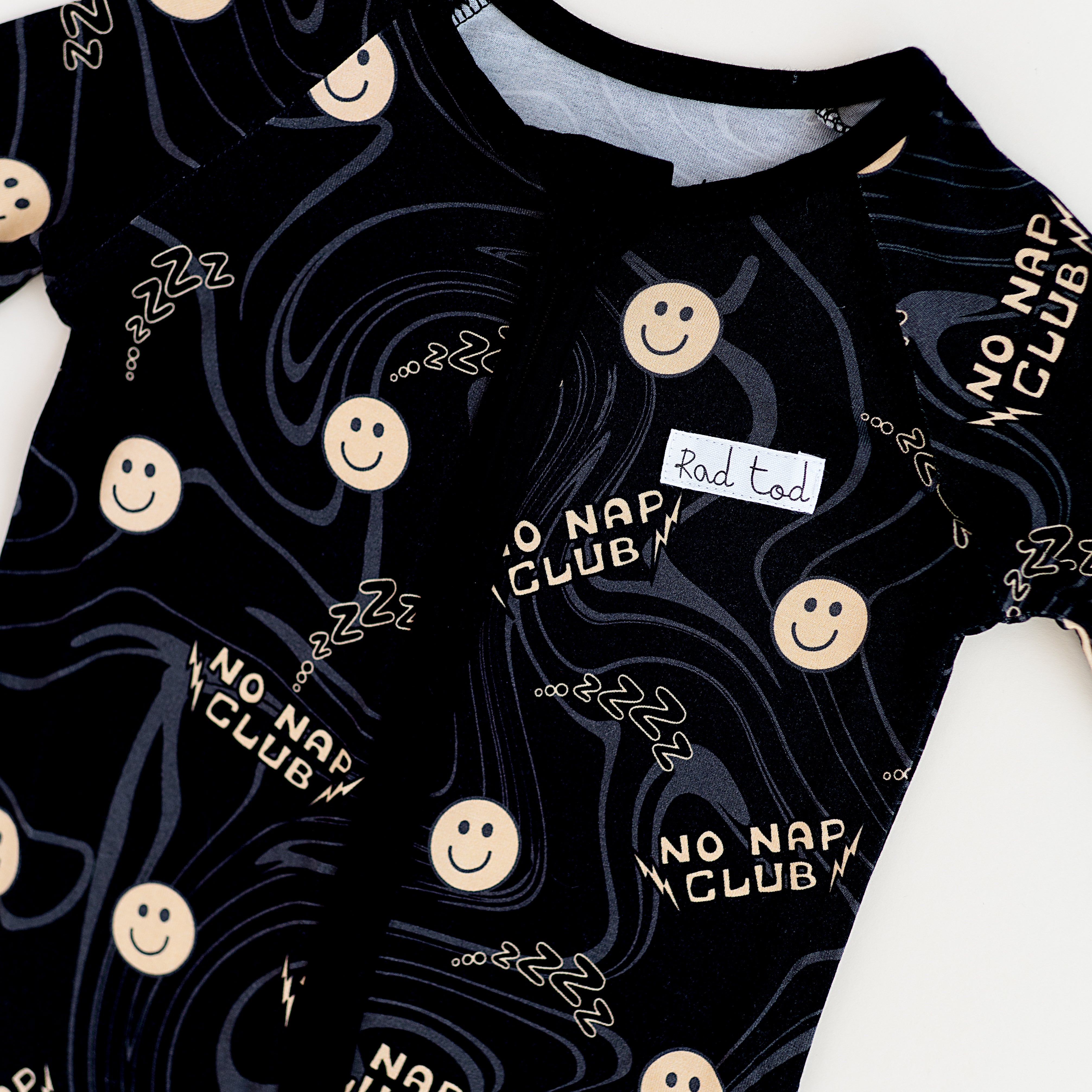 Trendy black bamboo onesie with smiley face design and wavy lines for toddlers