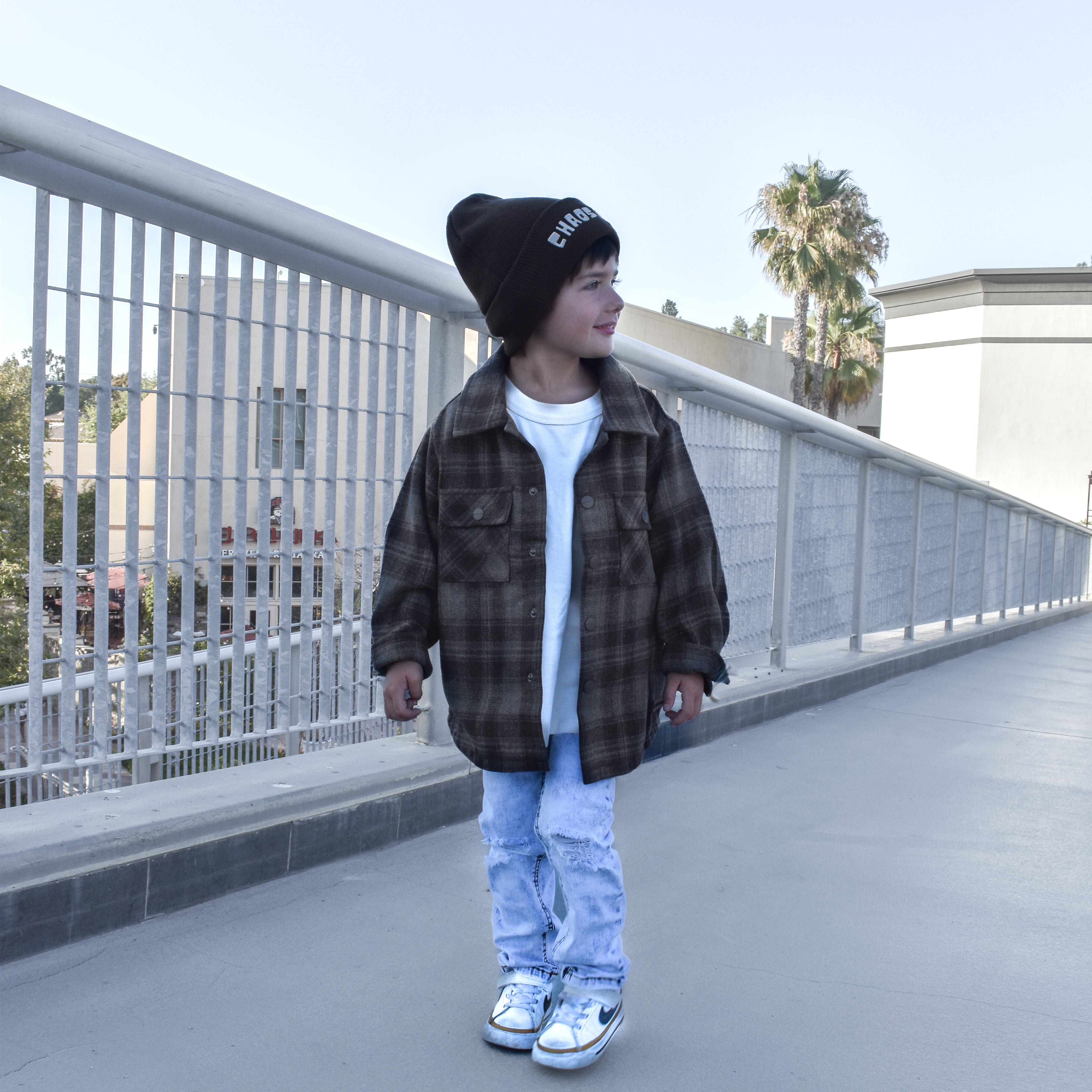 boy wearing espresso shacket standing by a fence