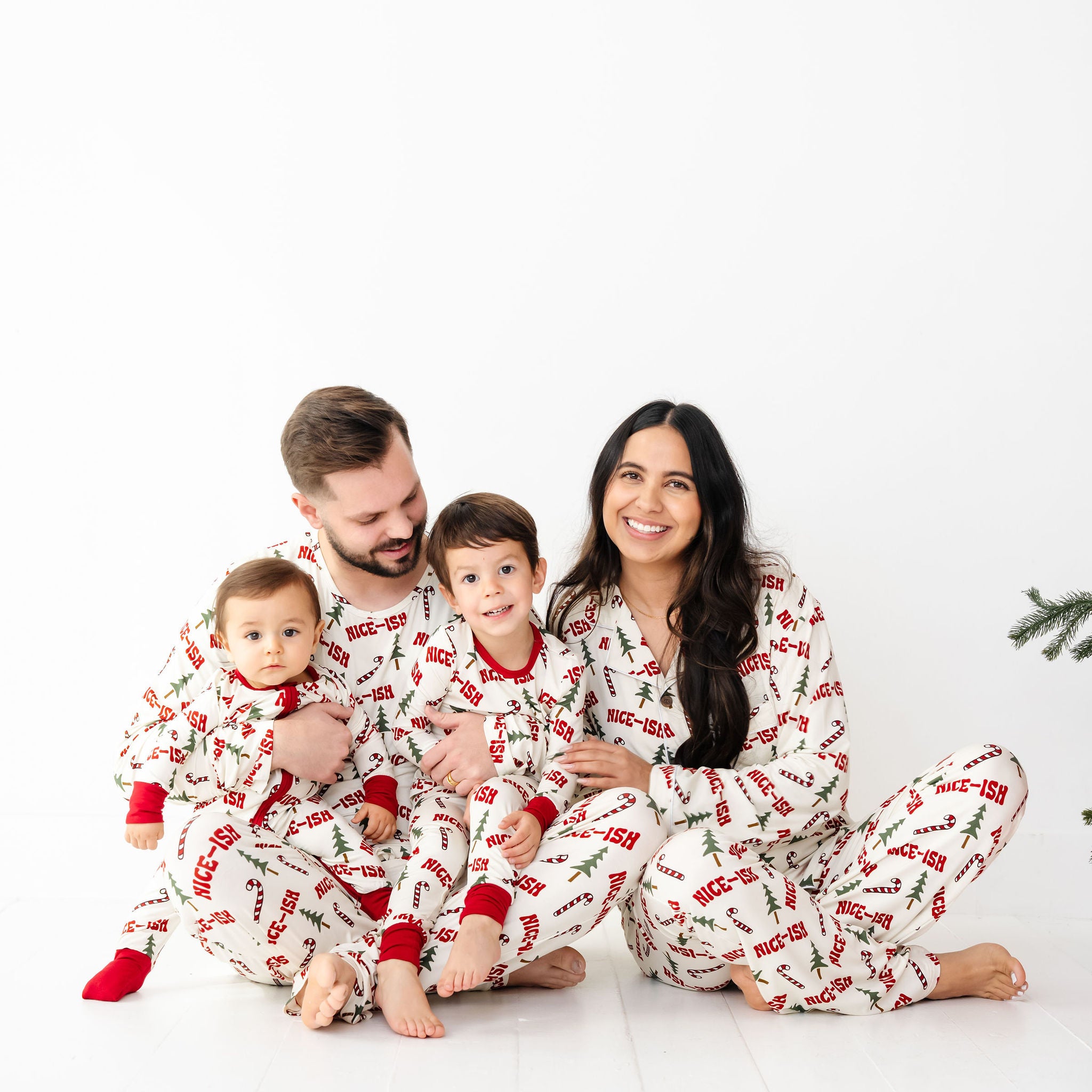 Family of four wearing matching pajamas on a white background