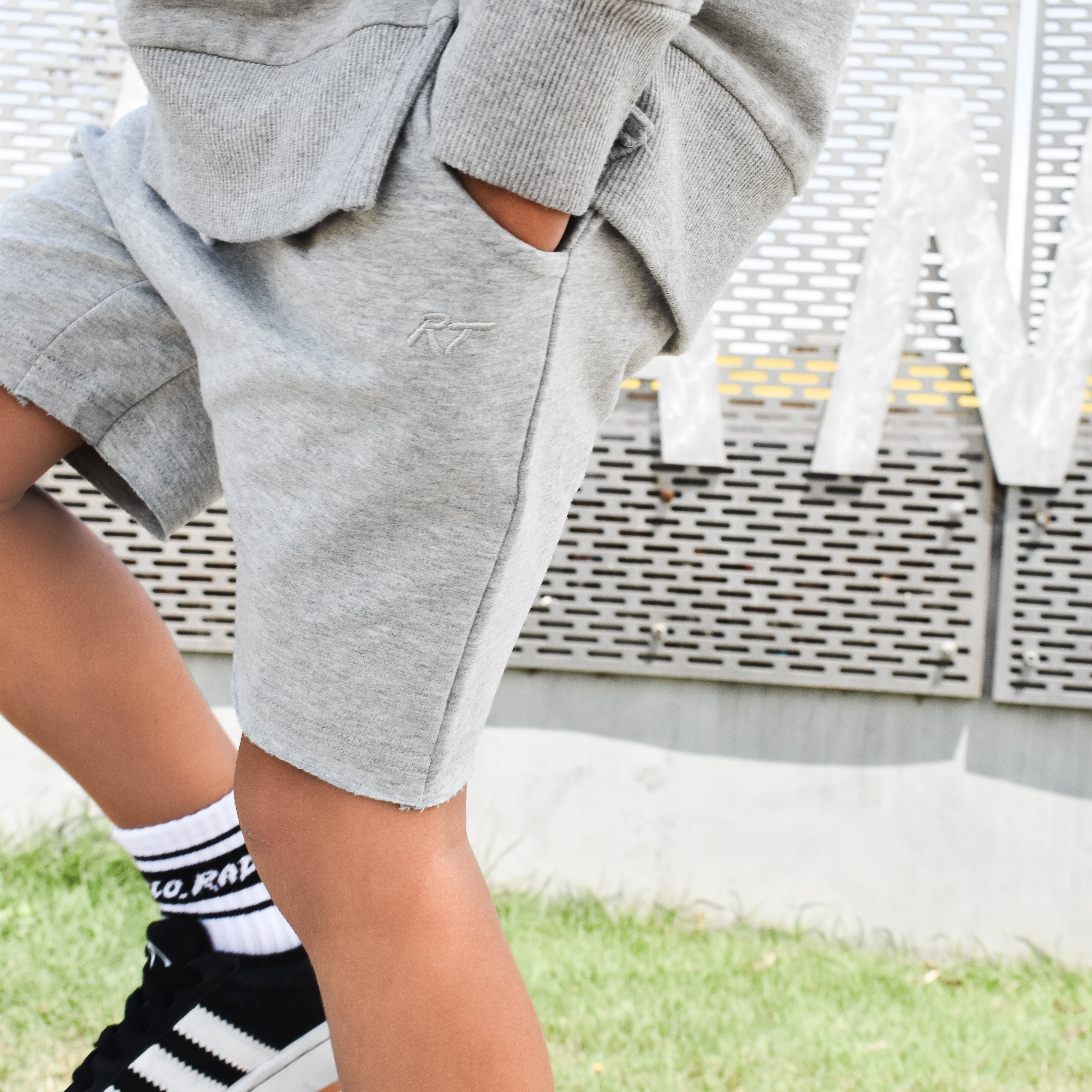 Young boy wearing gray Core Collection toddler shorts, standing outdoors and showcasing the relaxed, above-the-knee fit.