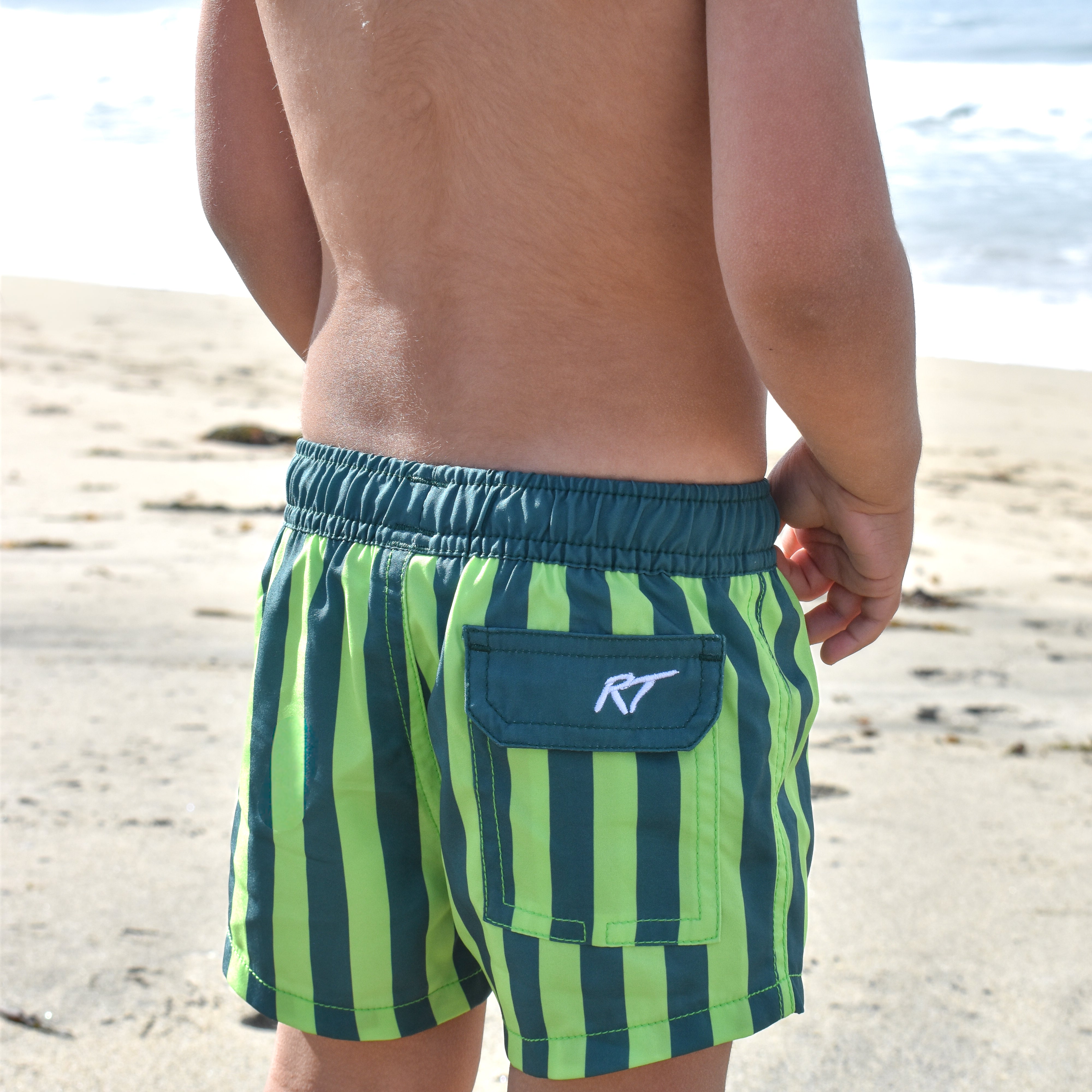 boy wearing green machine hi vis swimmie at the beach by Rad Toddler