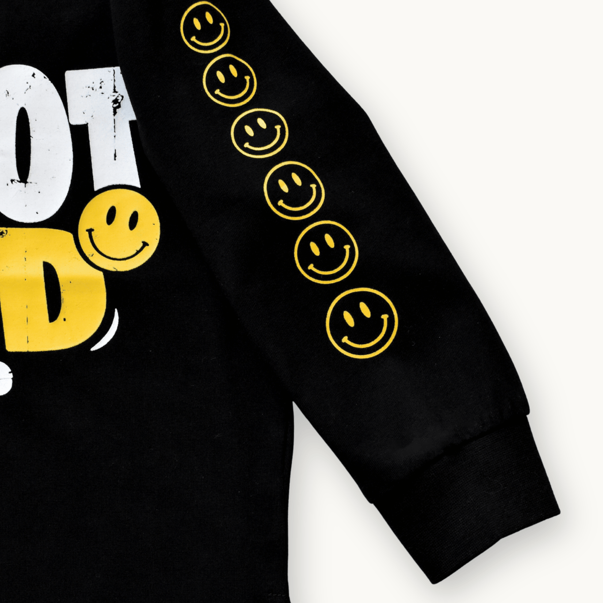 Close-up of a black long-sleeve sweatshirt with yellow smiley face graphics down one sleeve and a partial white and yellow graphic on the chest, shown on a light background.